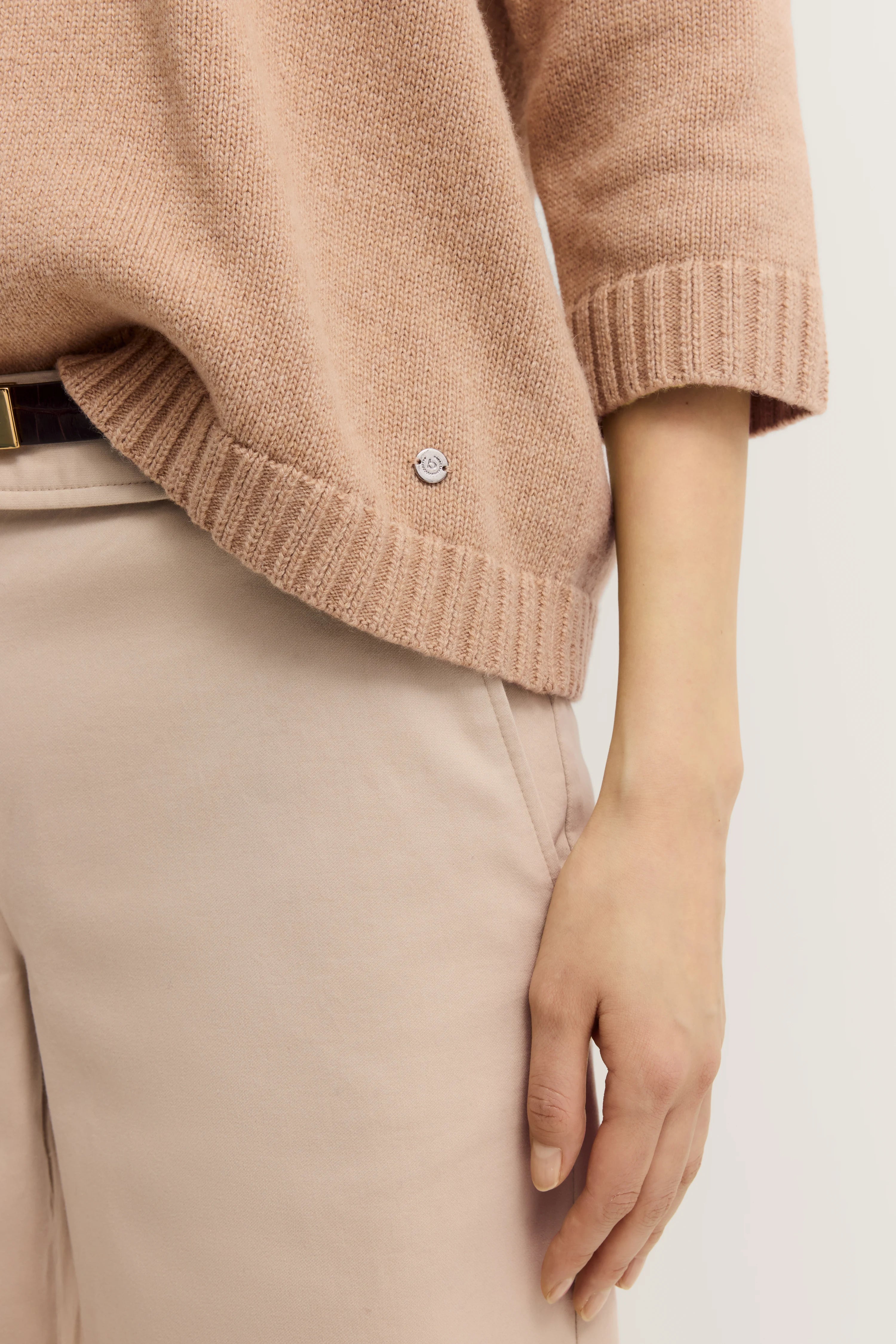 Beiger Strickpullover und Hose in Nahaufnahme, legeres Büstenbild.