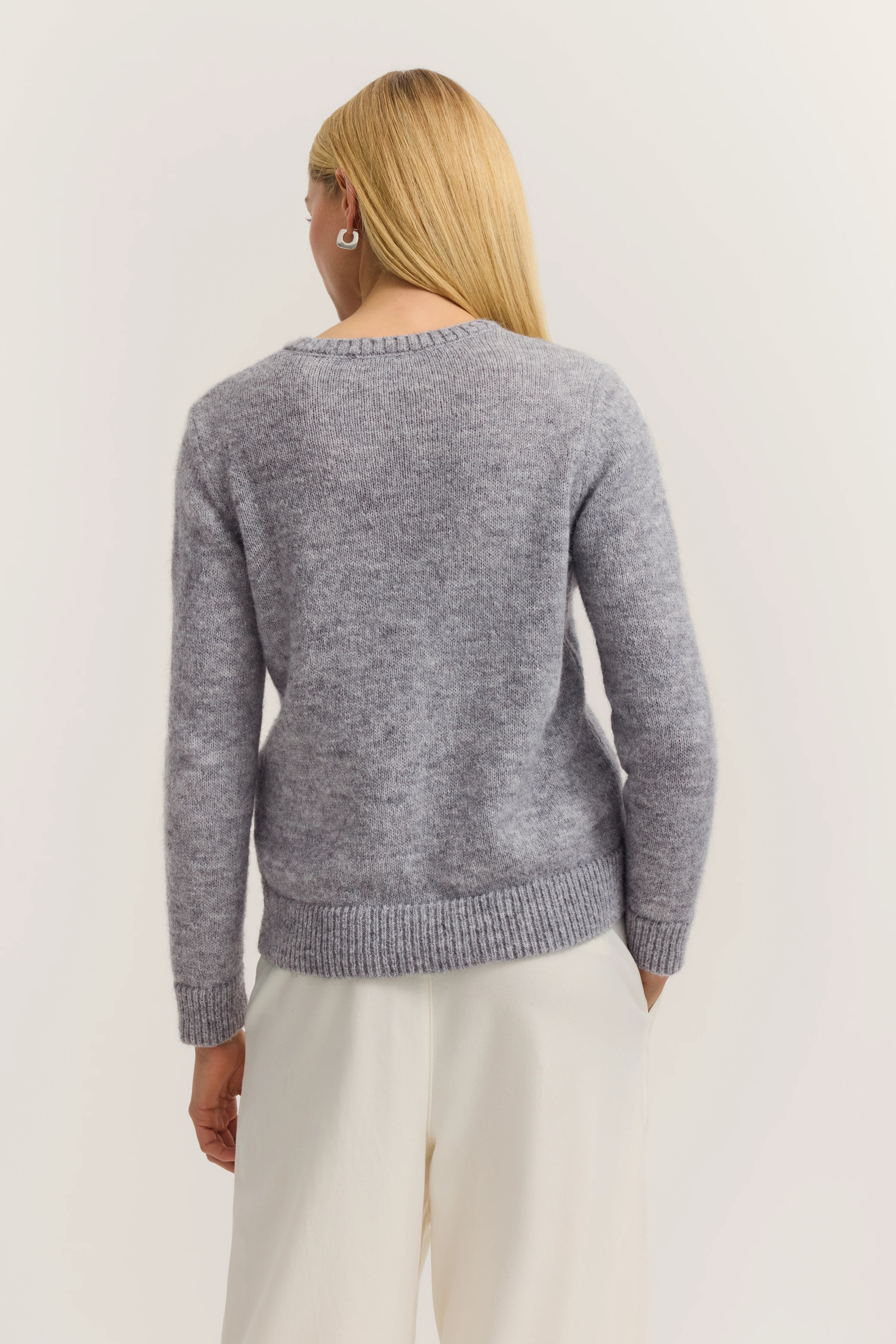 Gray sweater over white pants, back view, casual model image.