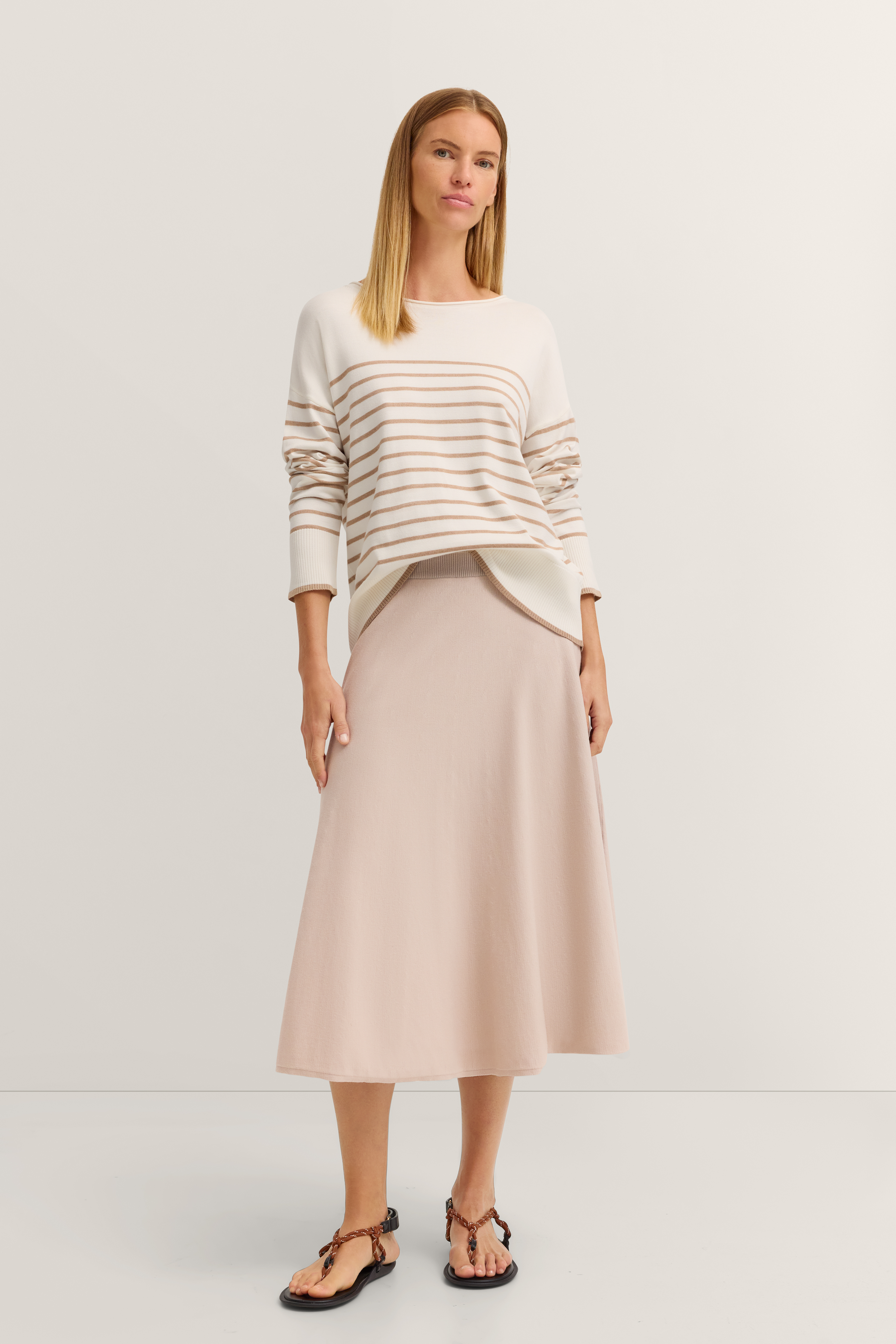 Dame im gestreiften Pullover und beige Rock, entspanntes Modelposing, bugatti Stil.