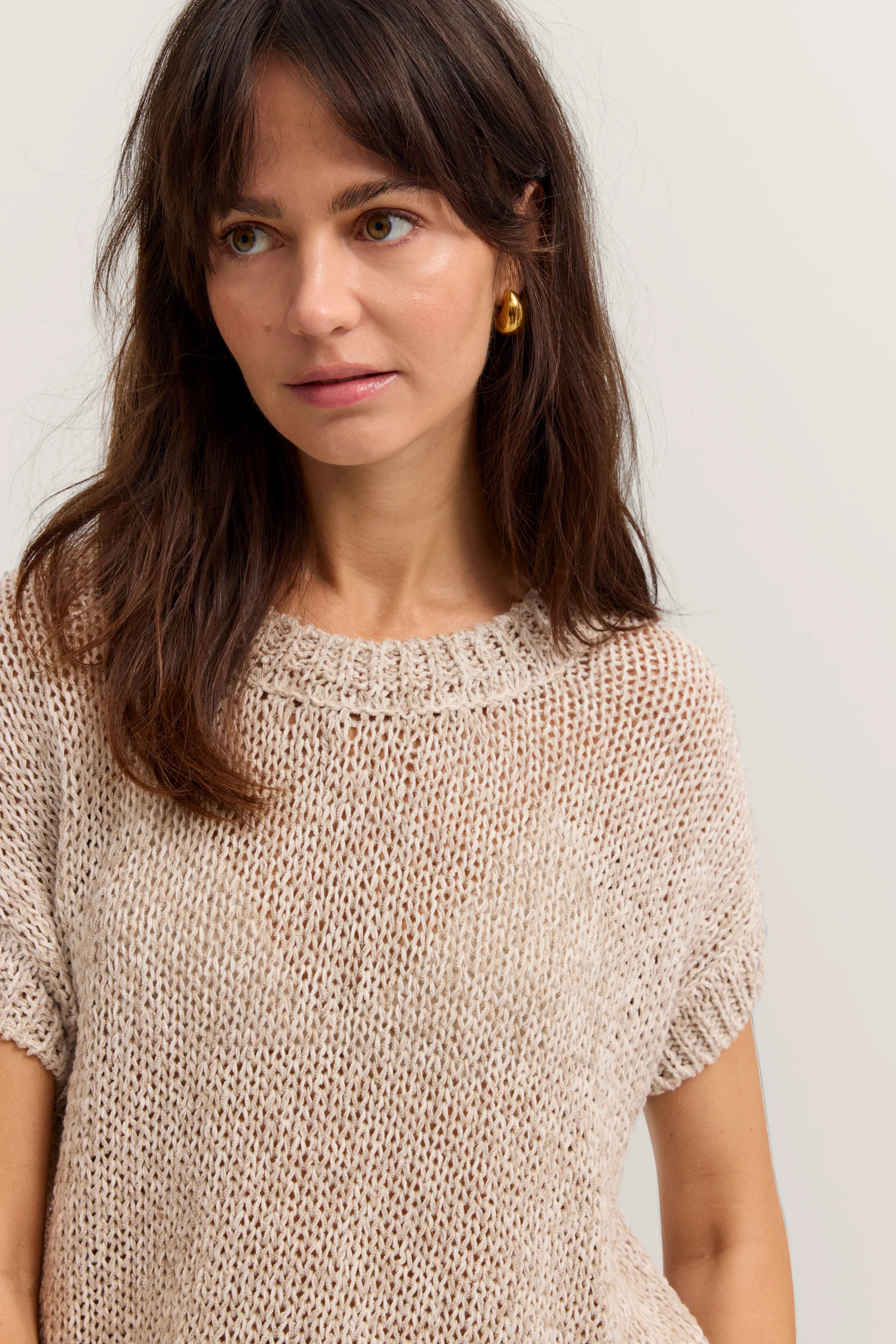 Beige Stricktop von bugatti, legeres Modelbild, sanft lächelnd, goldene Ohrringe