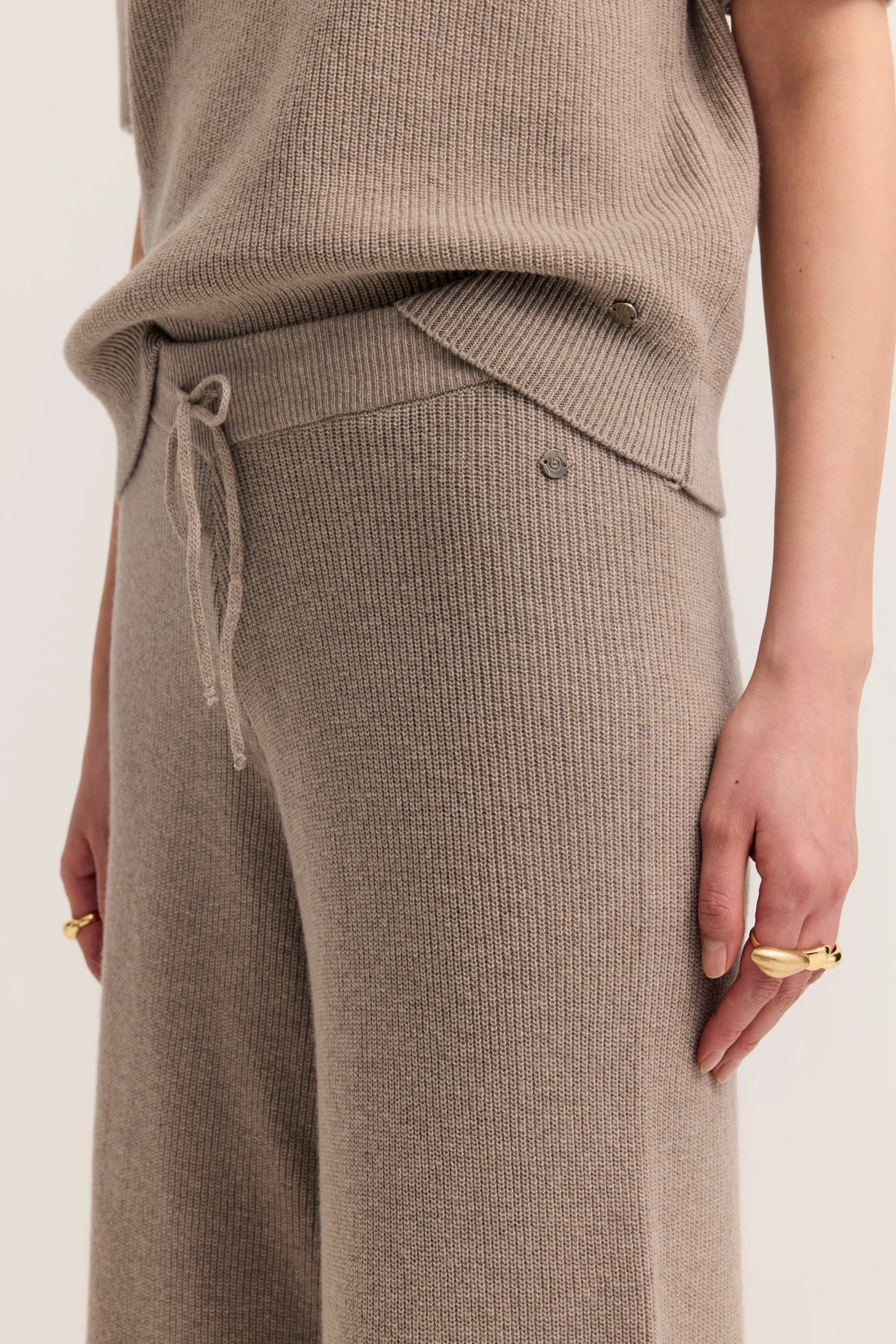 Strickoutfit in Beige, bestehend aus Oberteil und Hose, leger präsentiert.