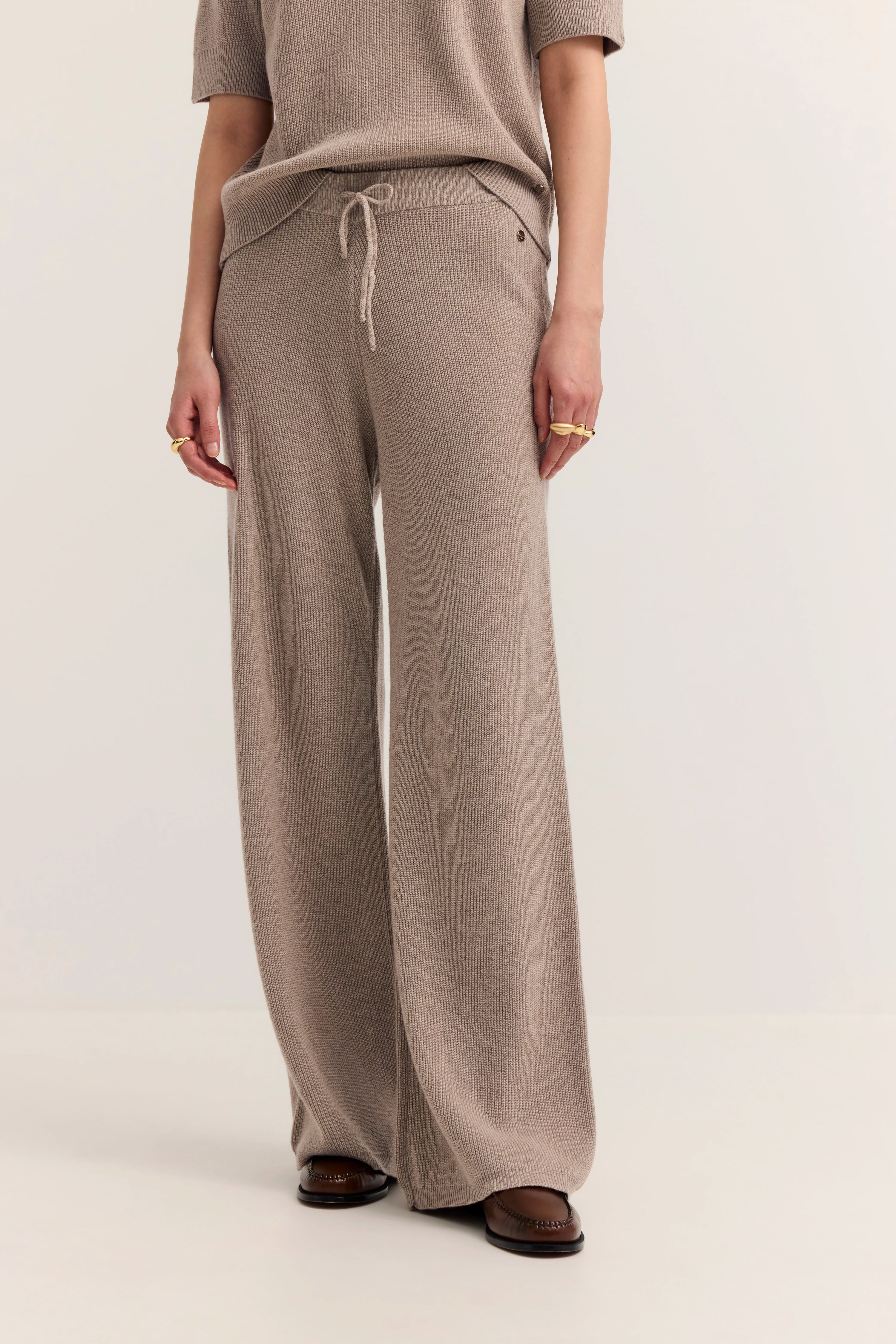bugatti Outfit mit beigefarbener Strickhose und lockerem Oberteil, legeres Modelbild, entspannte Pose.