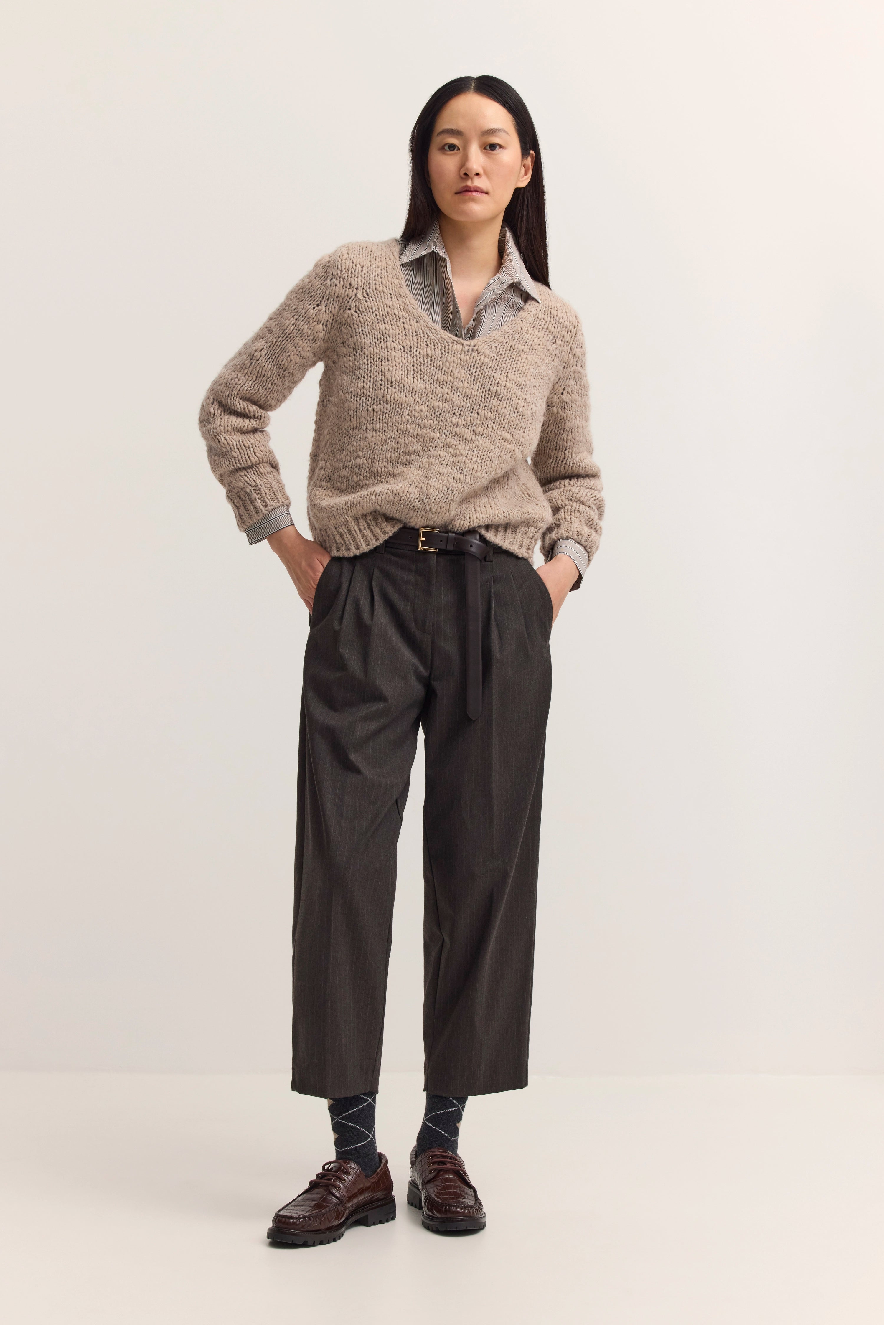 Model in beigem Pullover und grauer Hose von bugatti, lässiges Posing mit Händen in Hosentaschen.