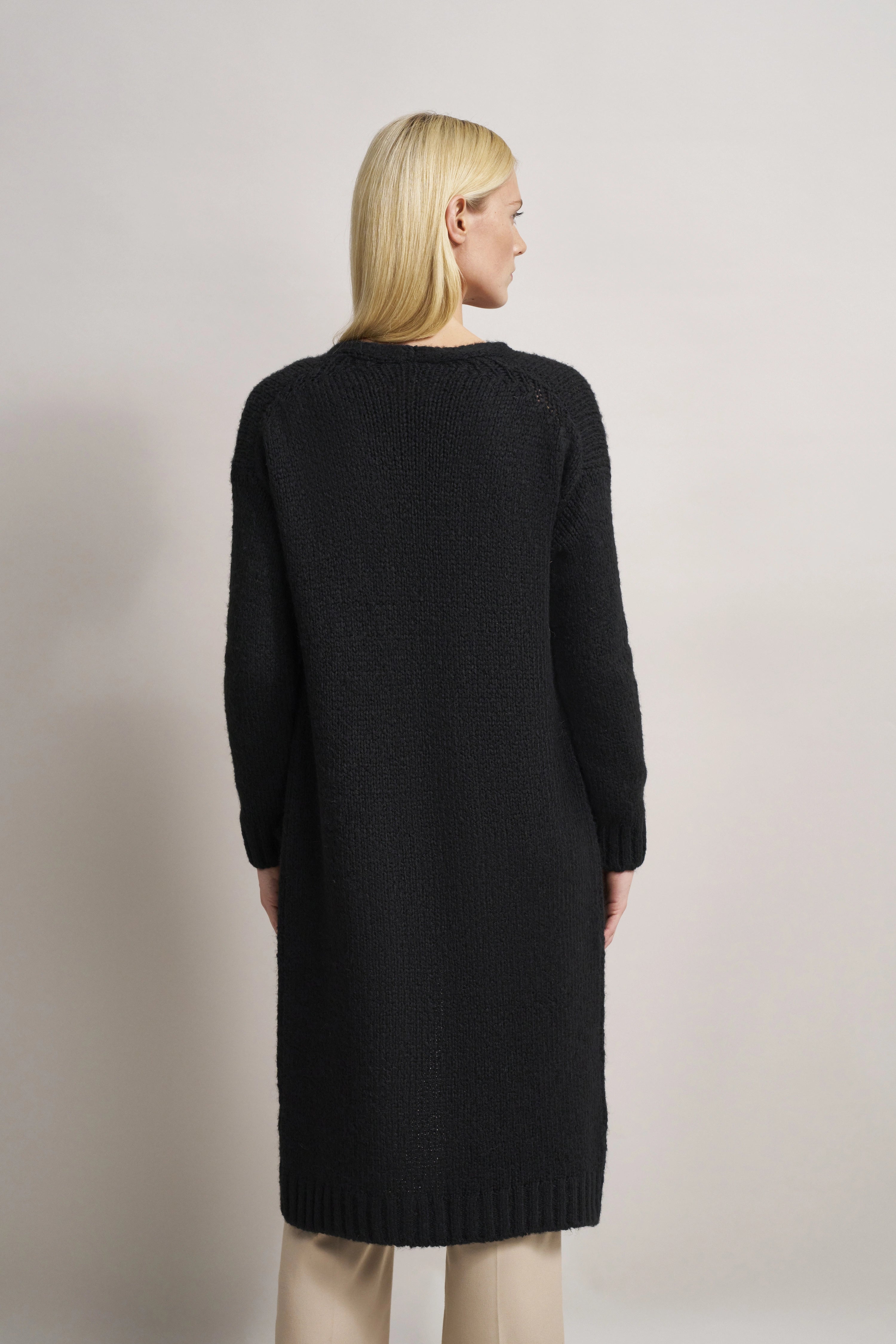 Schwarzes bugatti Strickkleid, Model von hinten, legeres Outfit, beige Hose.