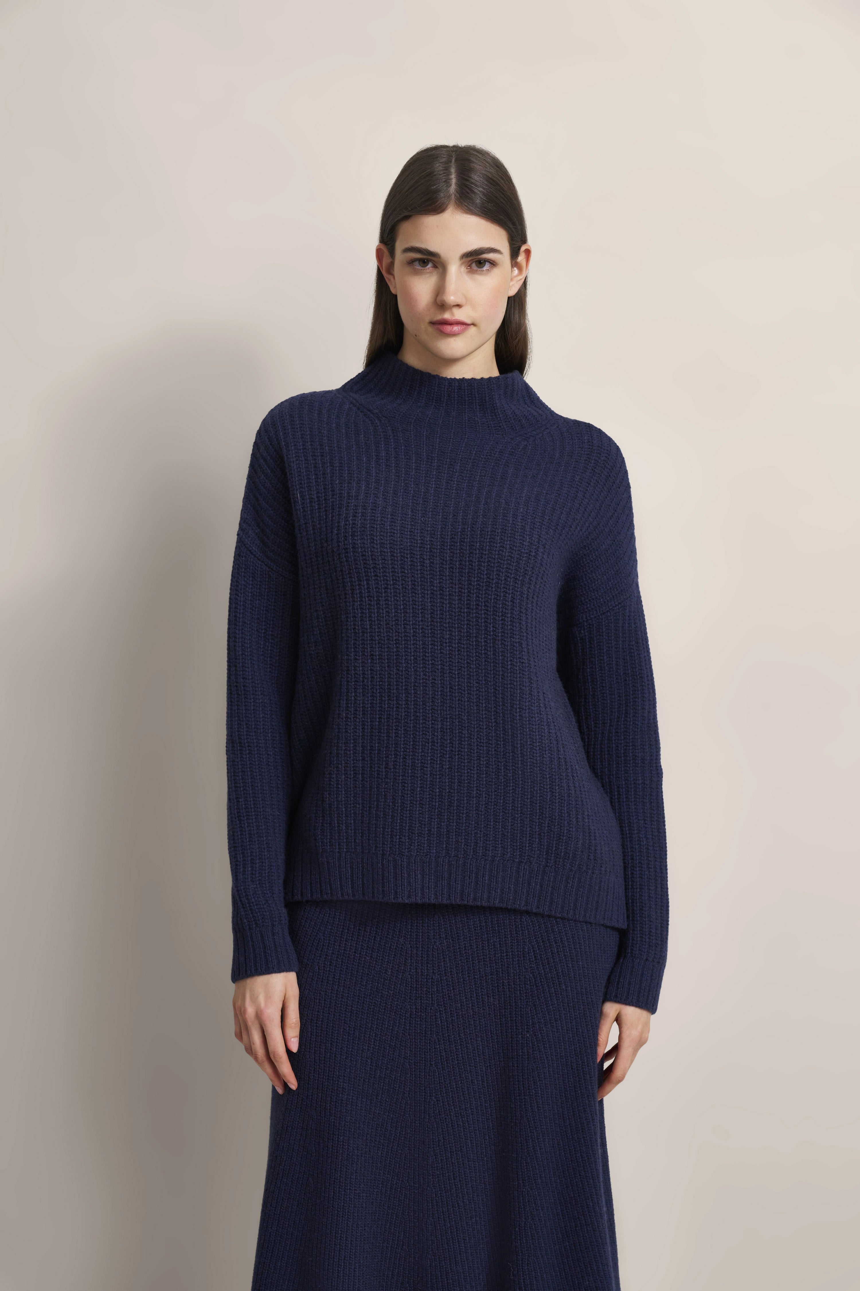 Dark blue bugatti knit sweater and skirt, model posing relaxed.