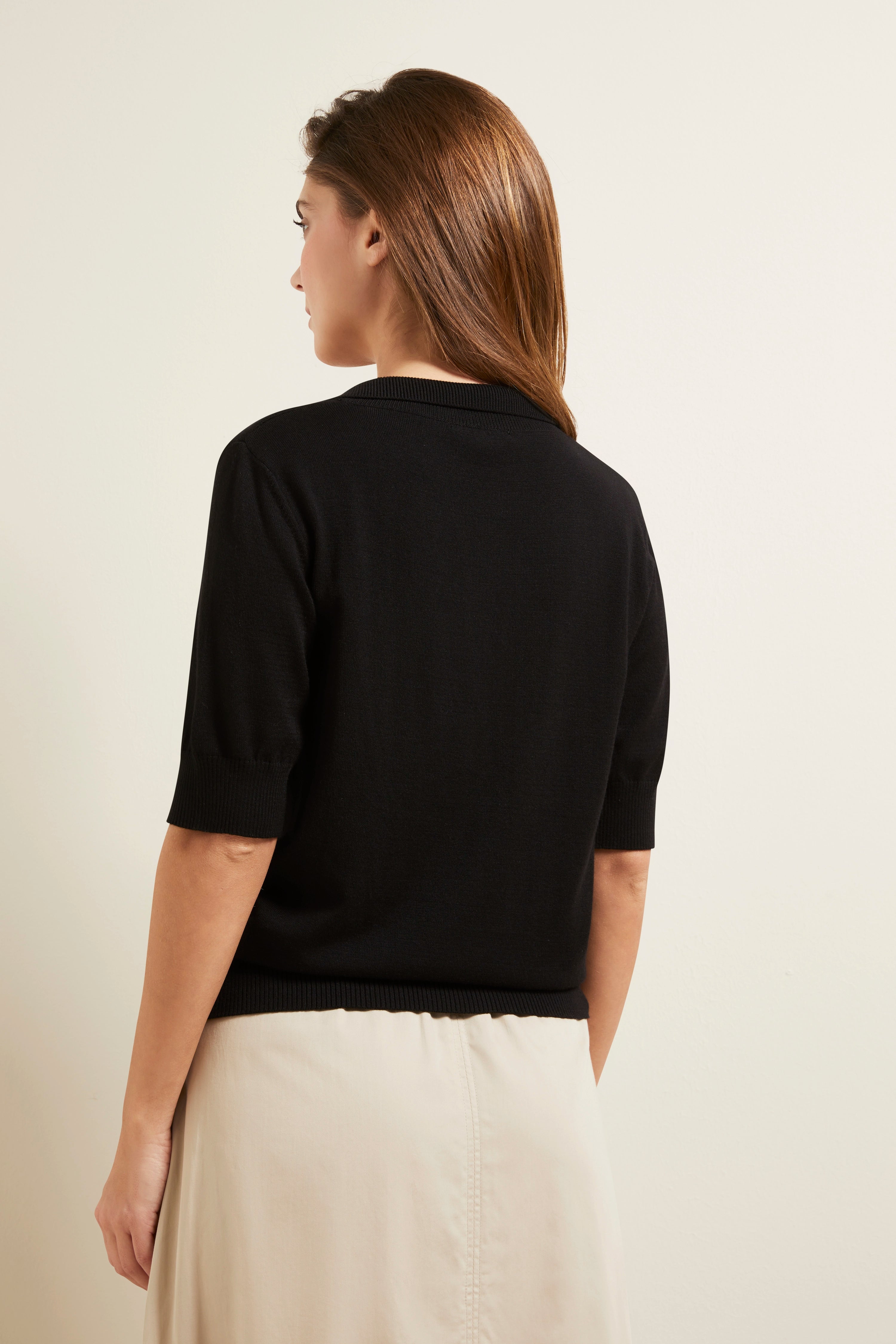 Schwarzer bugatti Pullover mit kurzen Ärmeln, beige Rock, seitliches Modelbild.