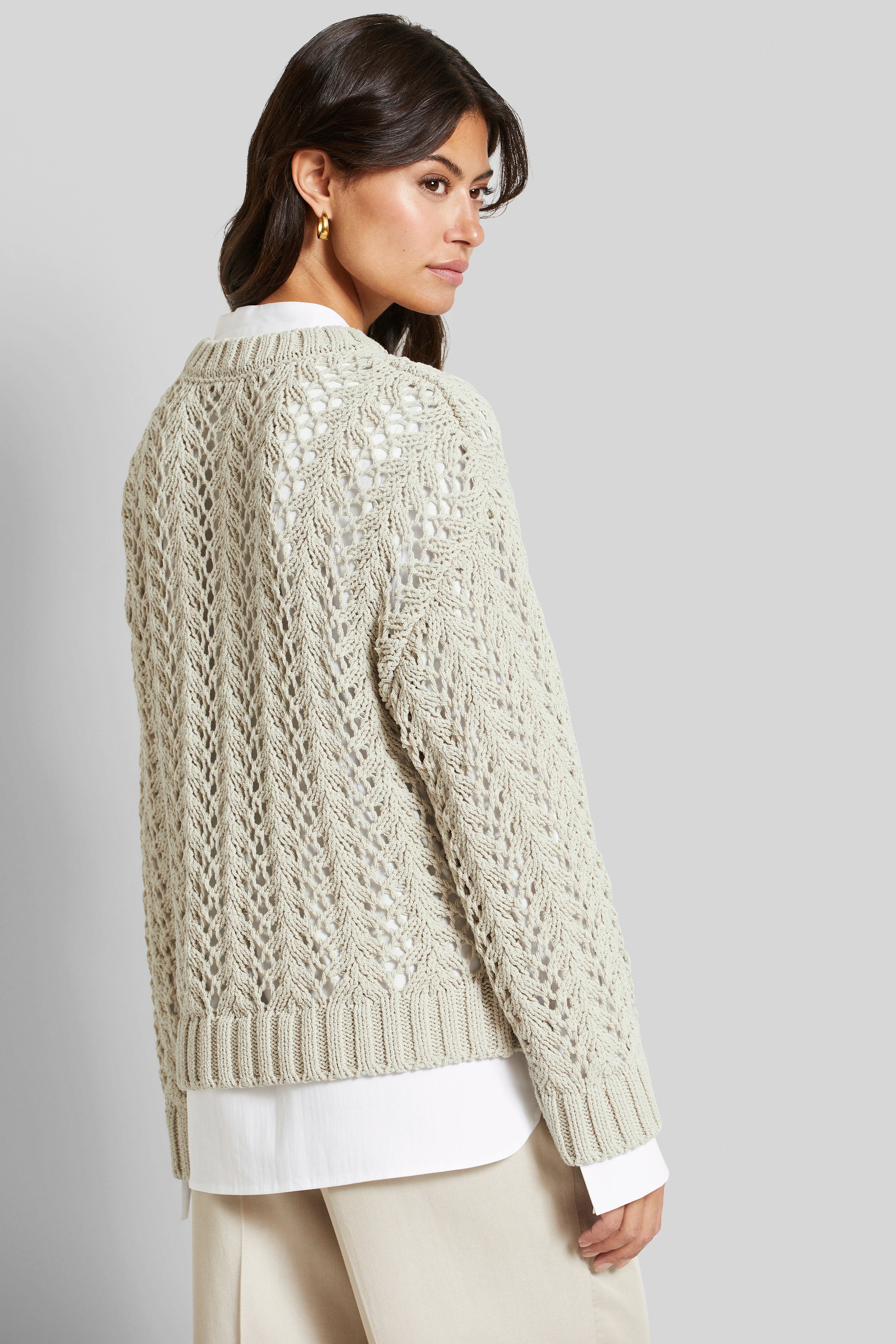 Beiger Strickpullover über weißer Bluse, Model im Profil, elegantes, entspanntes Outfit von bugatti.