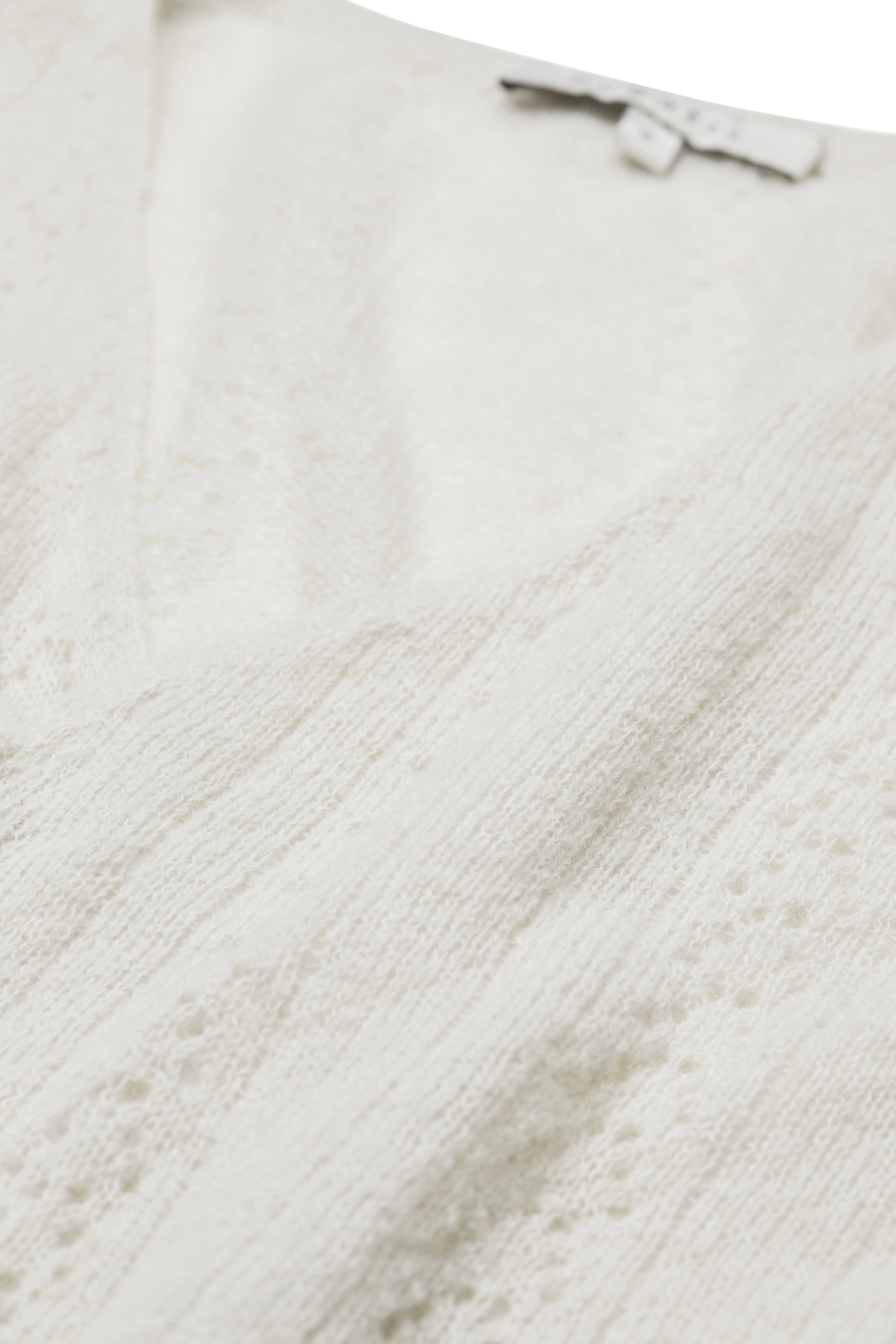 Weiße Stricktextur von bugatti, Detailansicht, zeigt feine Muster und hochwertige Verarbeitung.