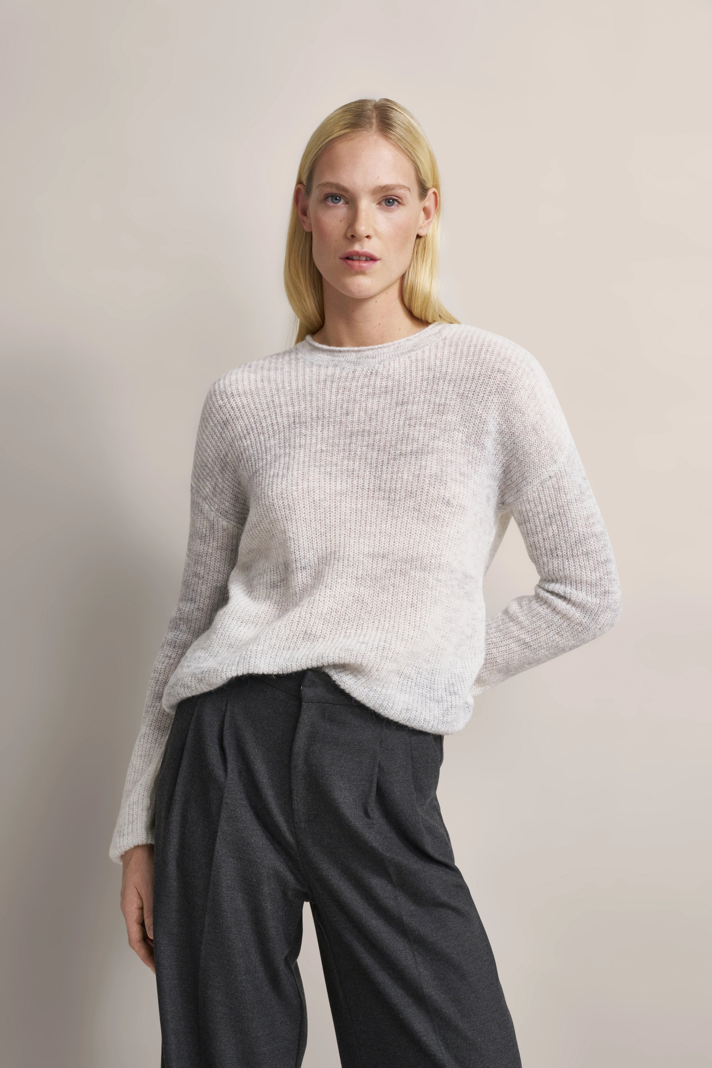 Model trägt hellen Strickpullover und dunkelgraue Hose von bugatti, lässig-elegante Pose.