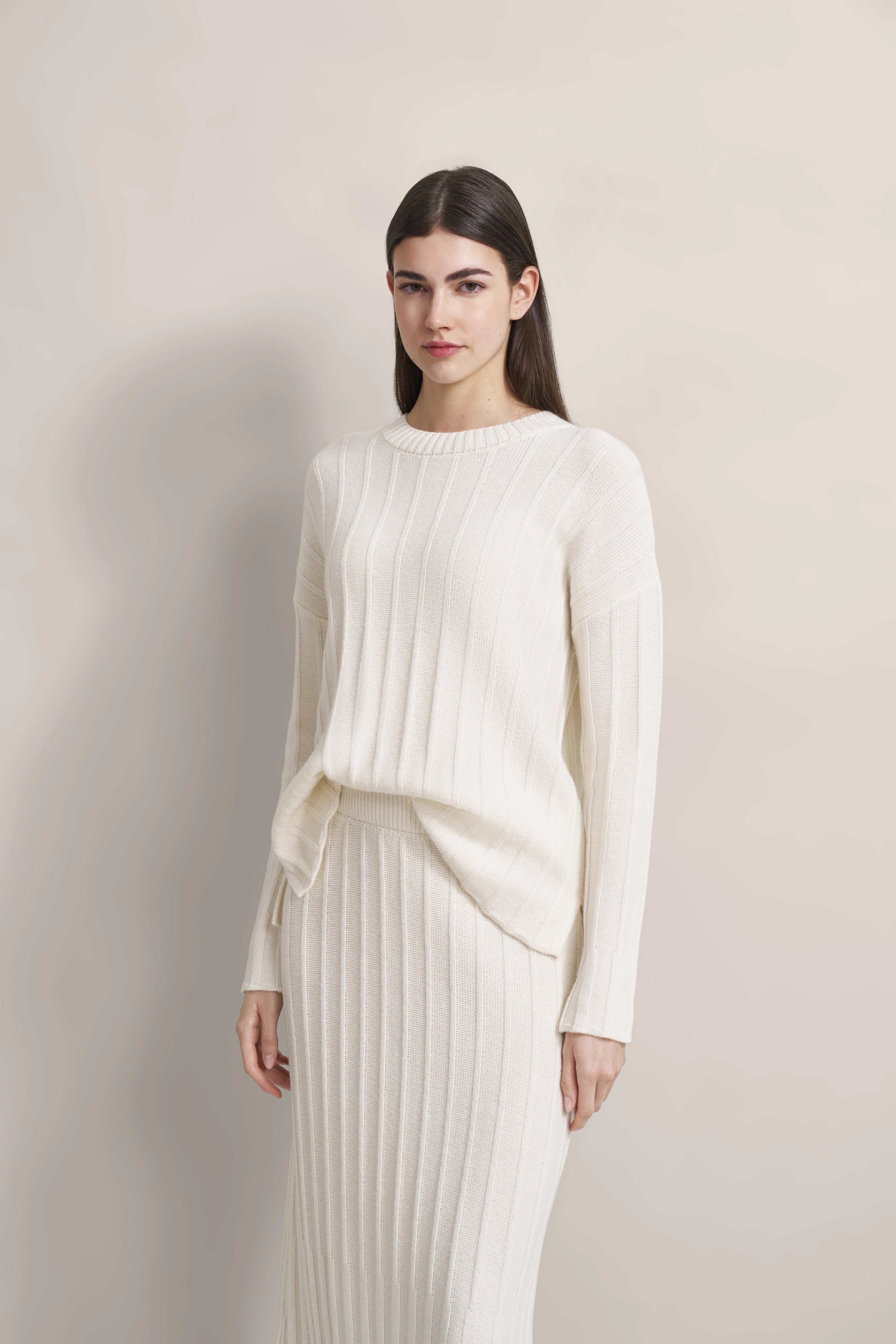 Weiße Strickkombi mit Pullover und Rock im Modelfoto, entspanntes Posing.