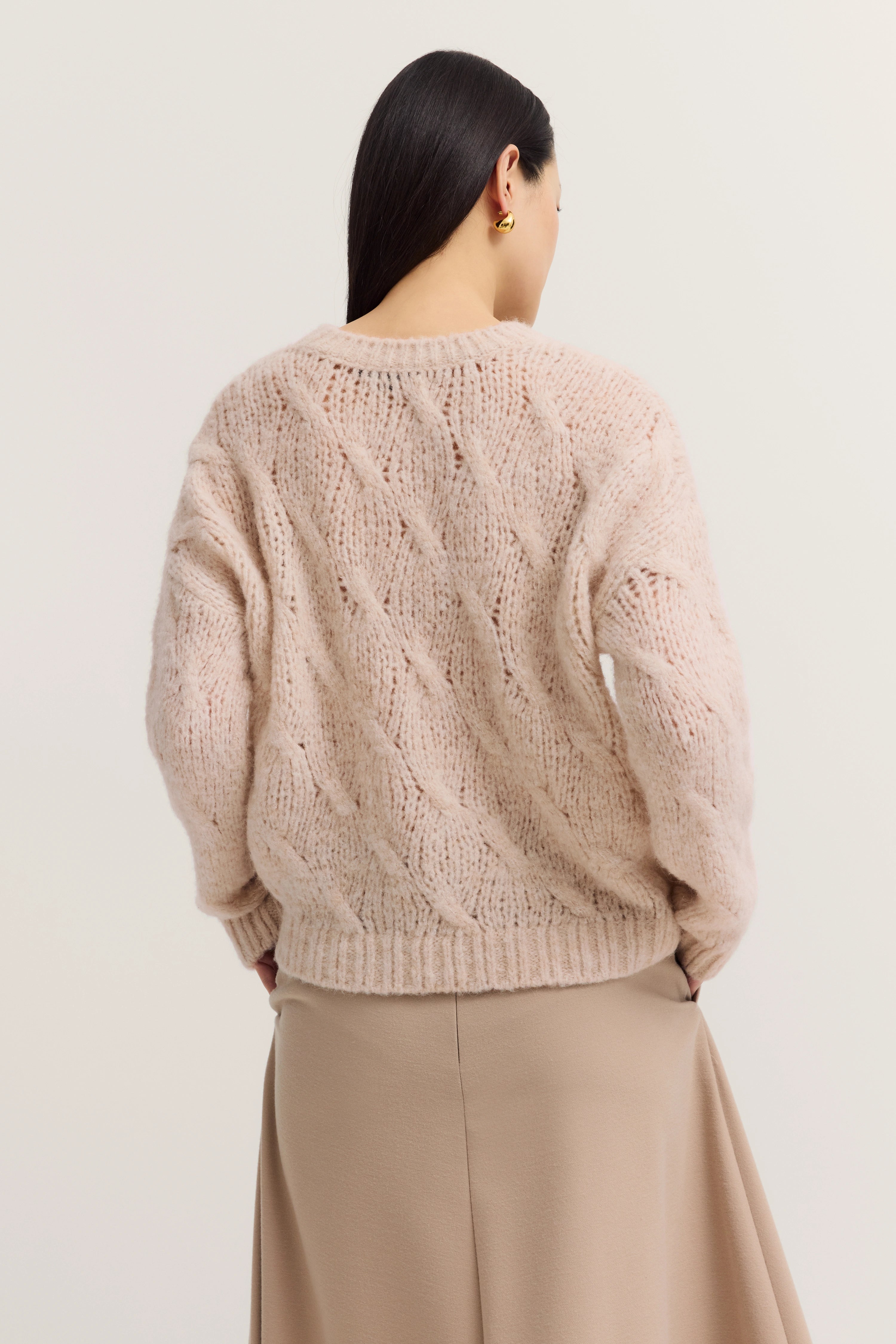 Beige cable knit sweater and skirt in casual model shot, back view.