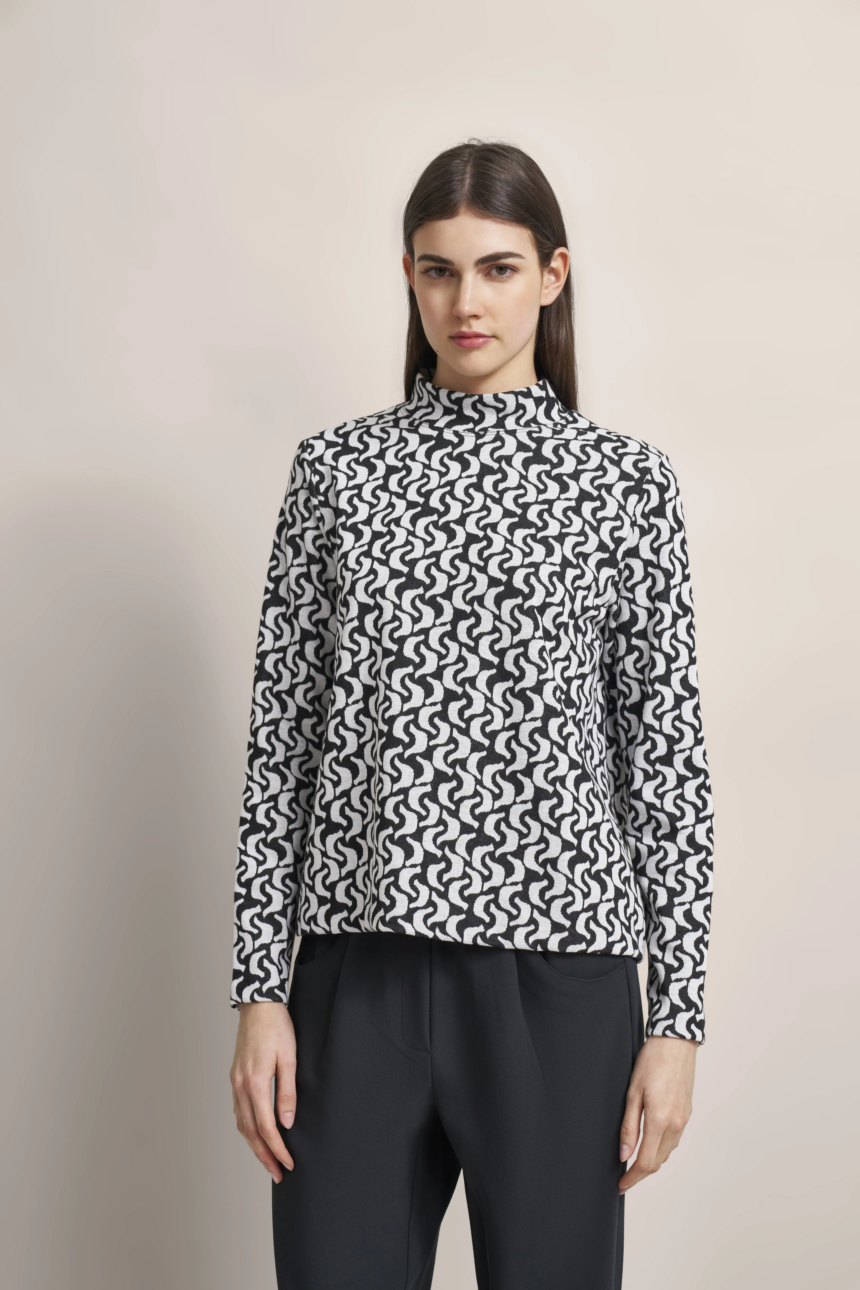 Model in schwarz-weiß gemustertem bugatti Pullover, legeres Posing, schwarze Hose.