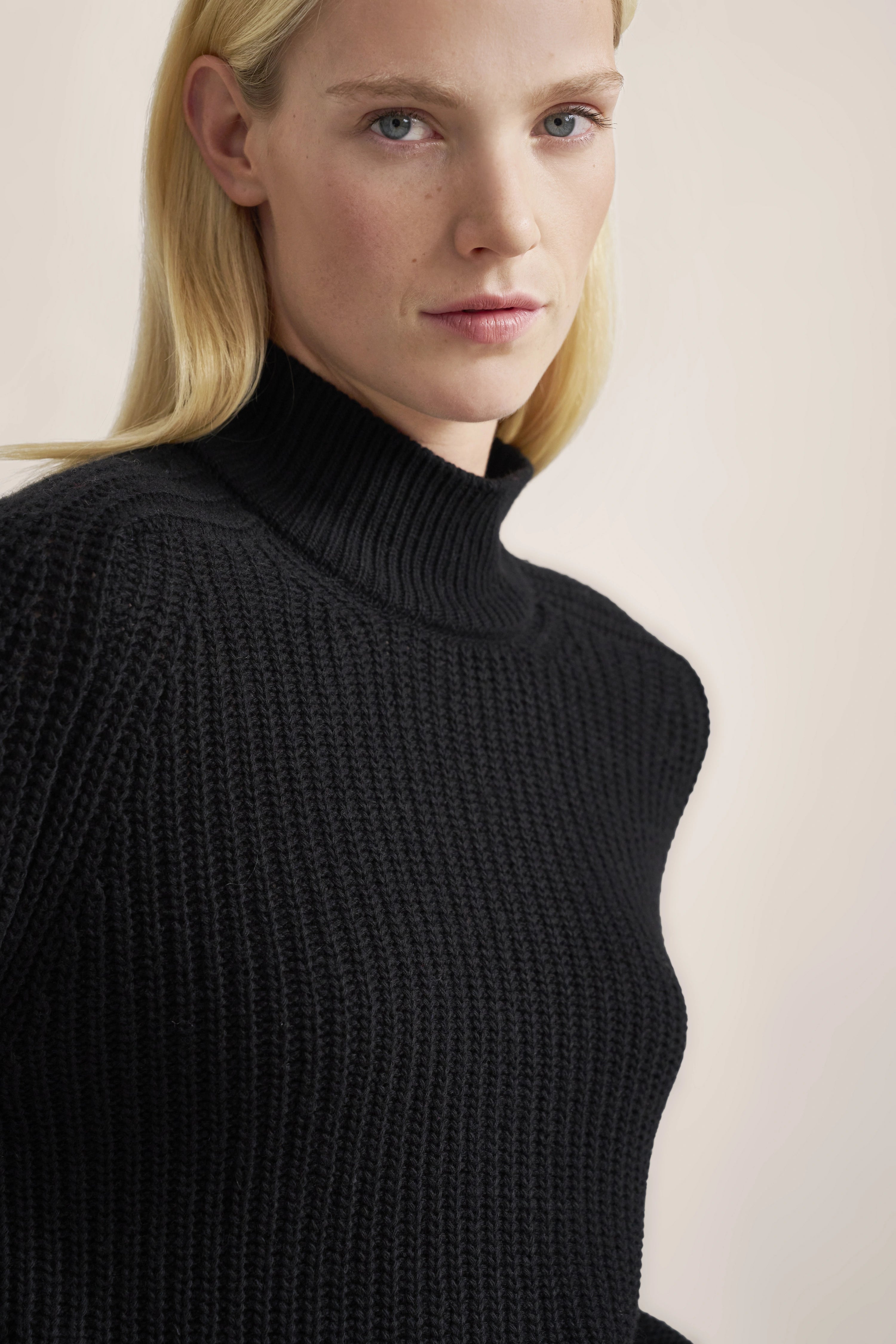 Büstenbild mit schwarzem Strickpullover, hoher Kragen, schlichtes Design, zeitlose Eleganz von bugatti.