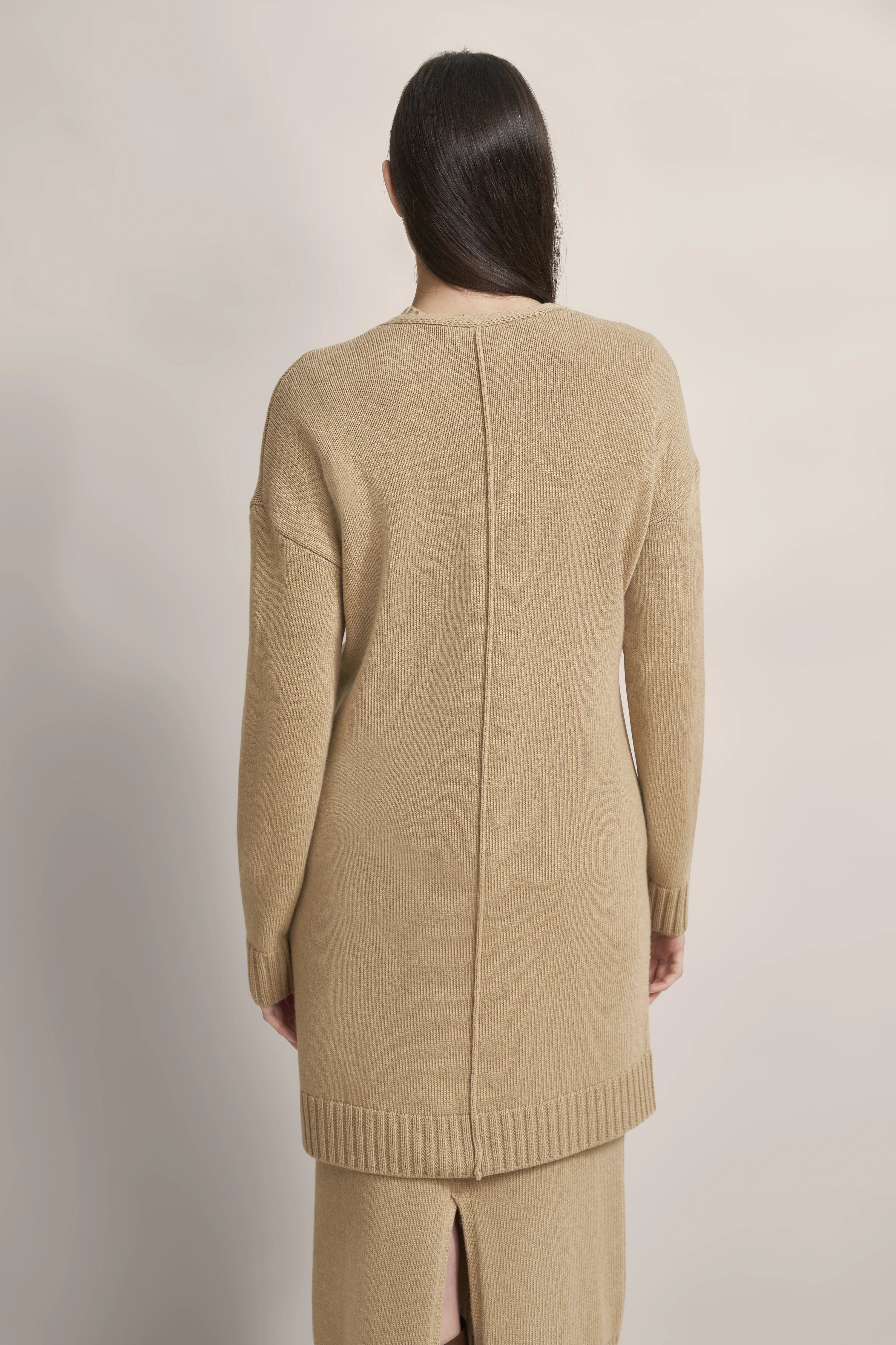 Long beige knit dress by bugatti, back view, model stands relaxed.