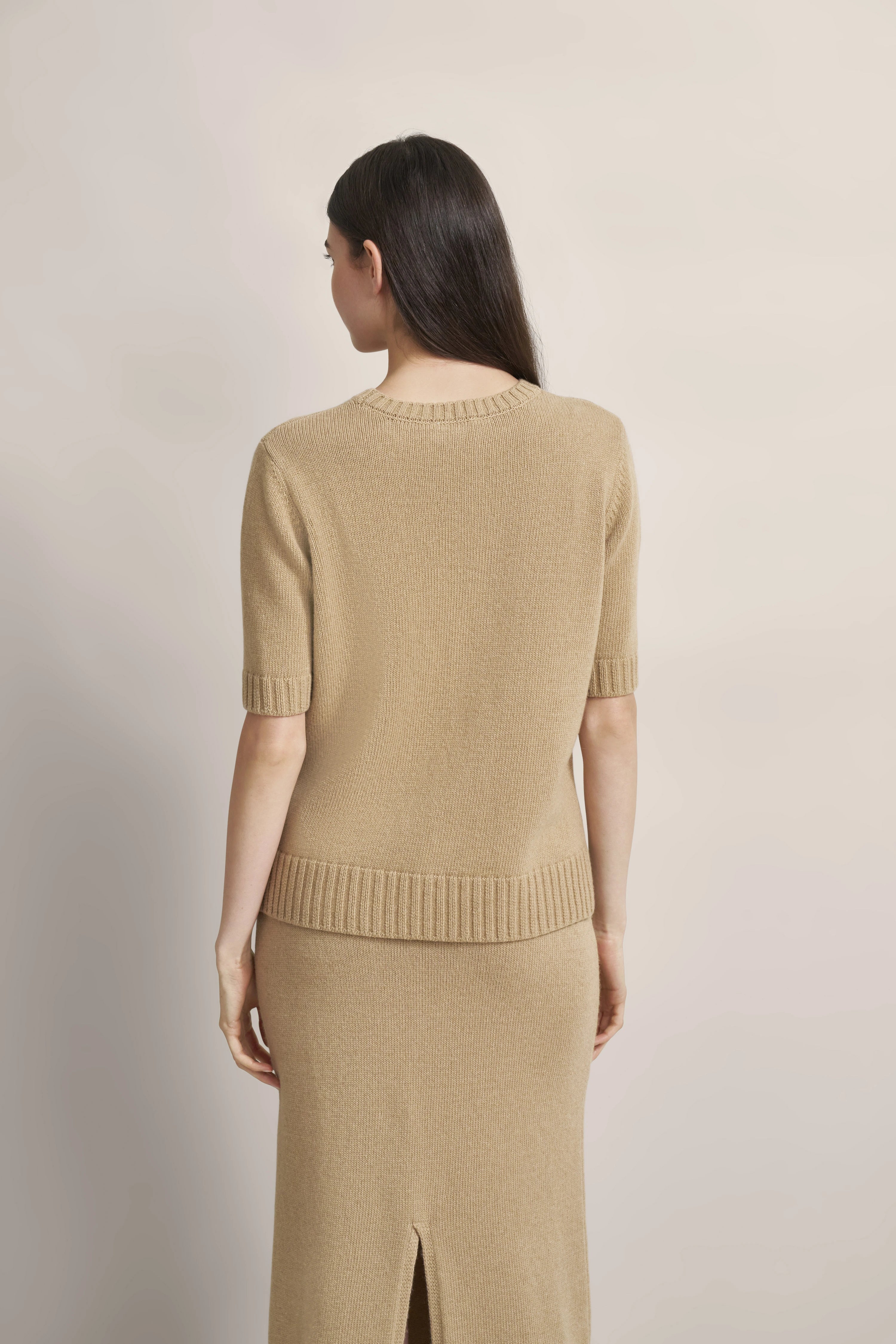 Beiger Strick-Zweiteiler aus Pullover und Rock, Modelbild von hinten, schlichtes Design.