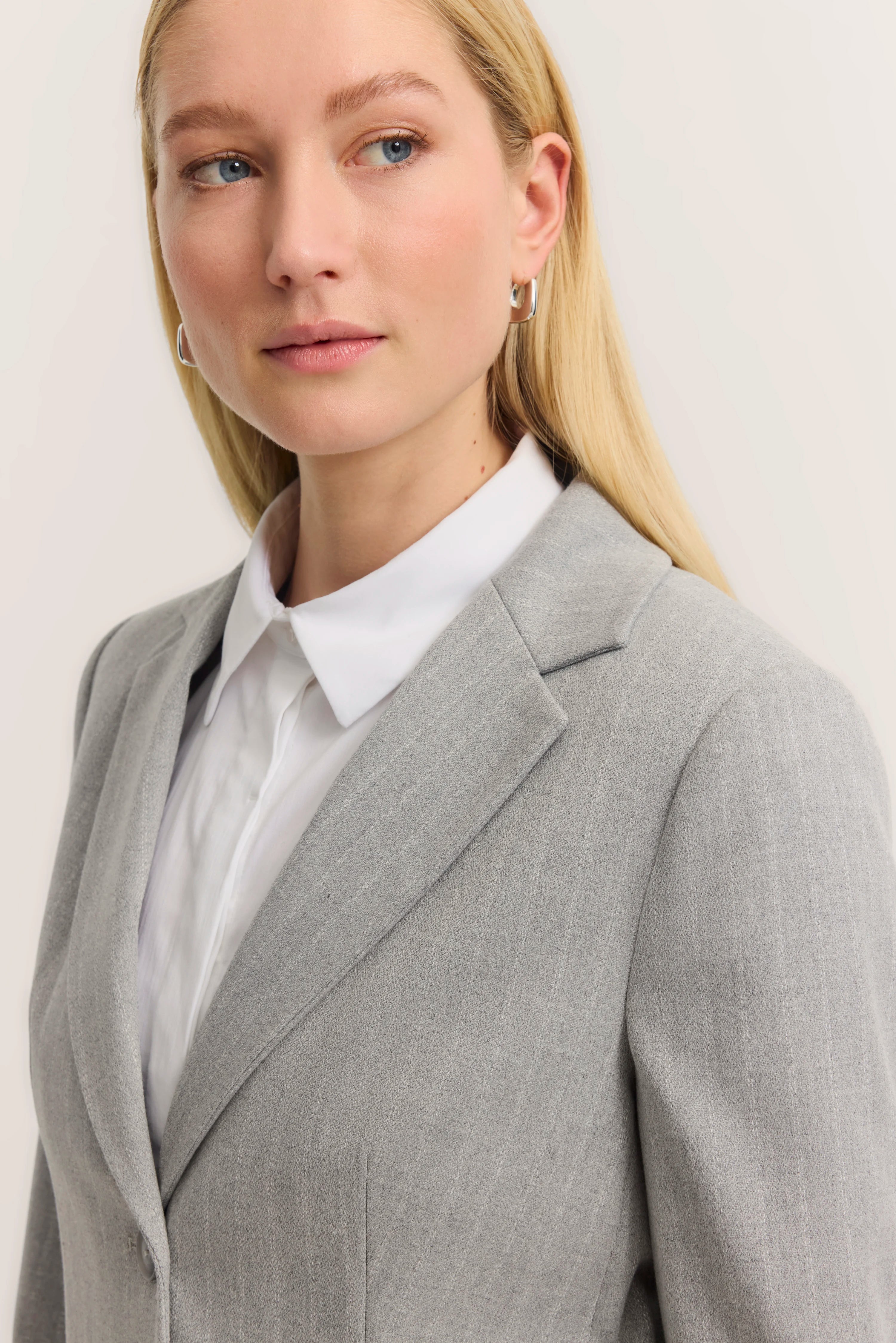 Grauer bugatti Blazer und weiße Bluse auf Model, Nahaufnahme, elegantes Posing.