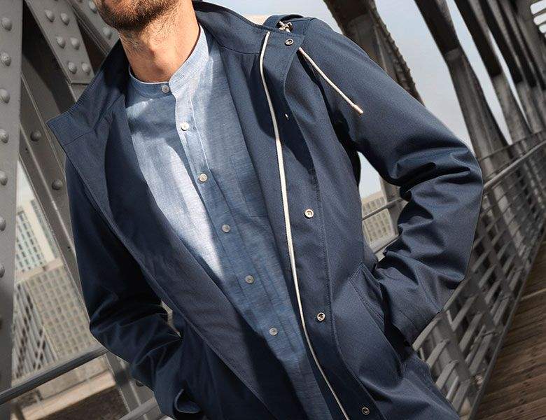 Ein Mann trägt eine dunkelblaue Funktionsjacke über einem hellblauen Stehkragenhemd. Der Look wirkt modern, wetterfest und stilvoll urban – ideal für aktive Tage.