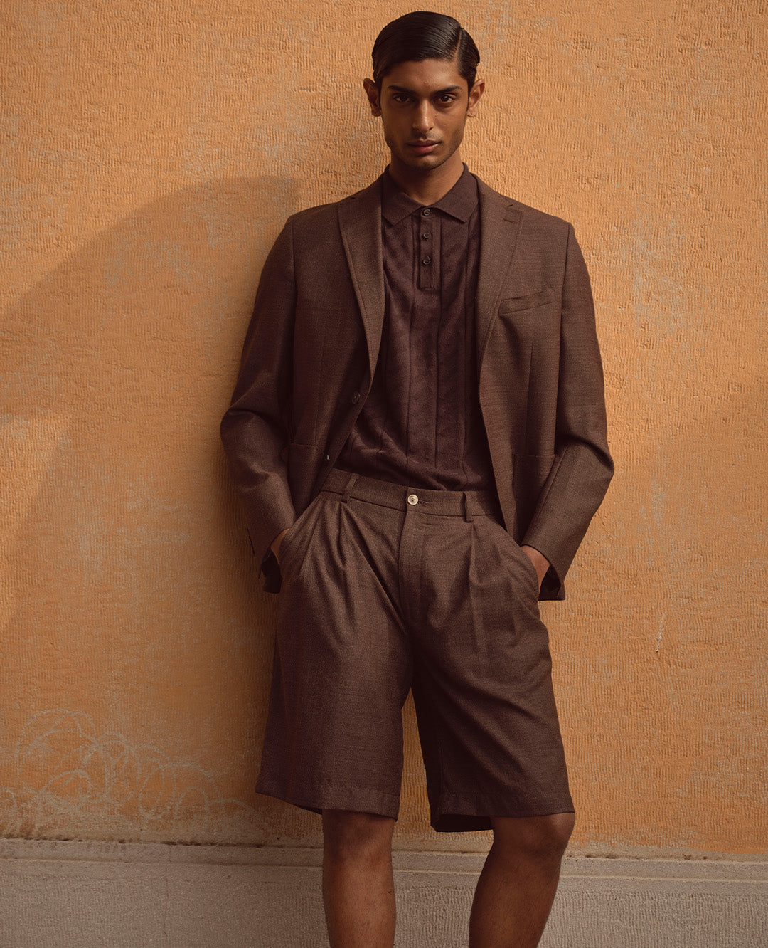 Ein Mann trägt ein braunes Sommer-Outfit mit Sakko, Poloshirt und Shorts. Der Look kombiniert Eleganz mit moderner Leichtigkeit und stilvoller Nonchalance.
