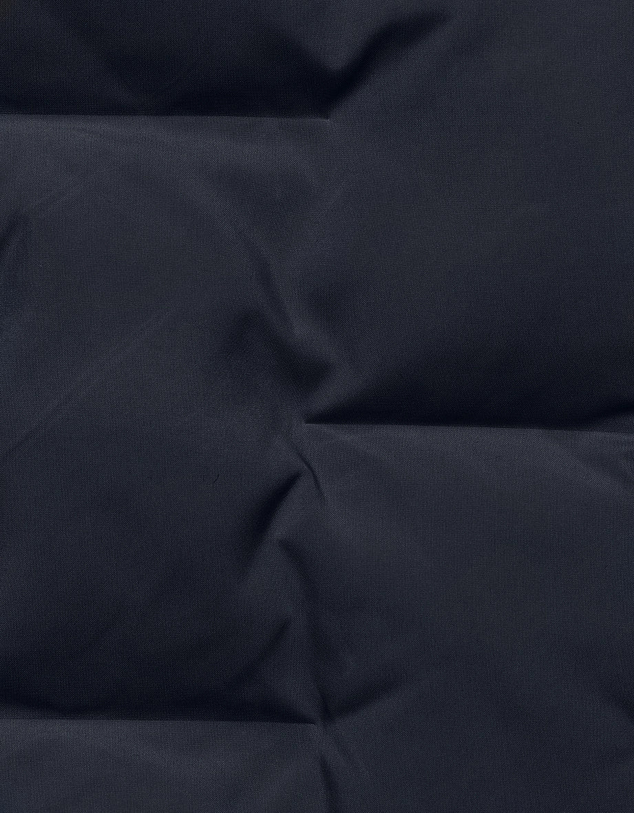 Dunkelblauer Stoff mit Steppnähten, Detailaufnahme, Struktur sichtbar.