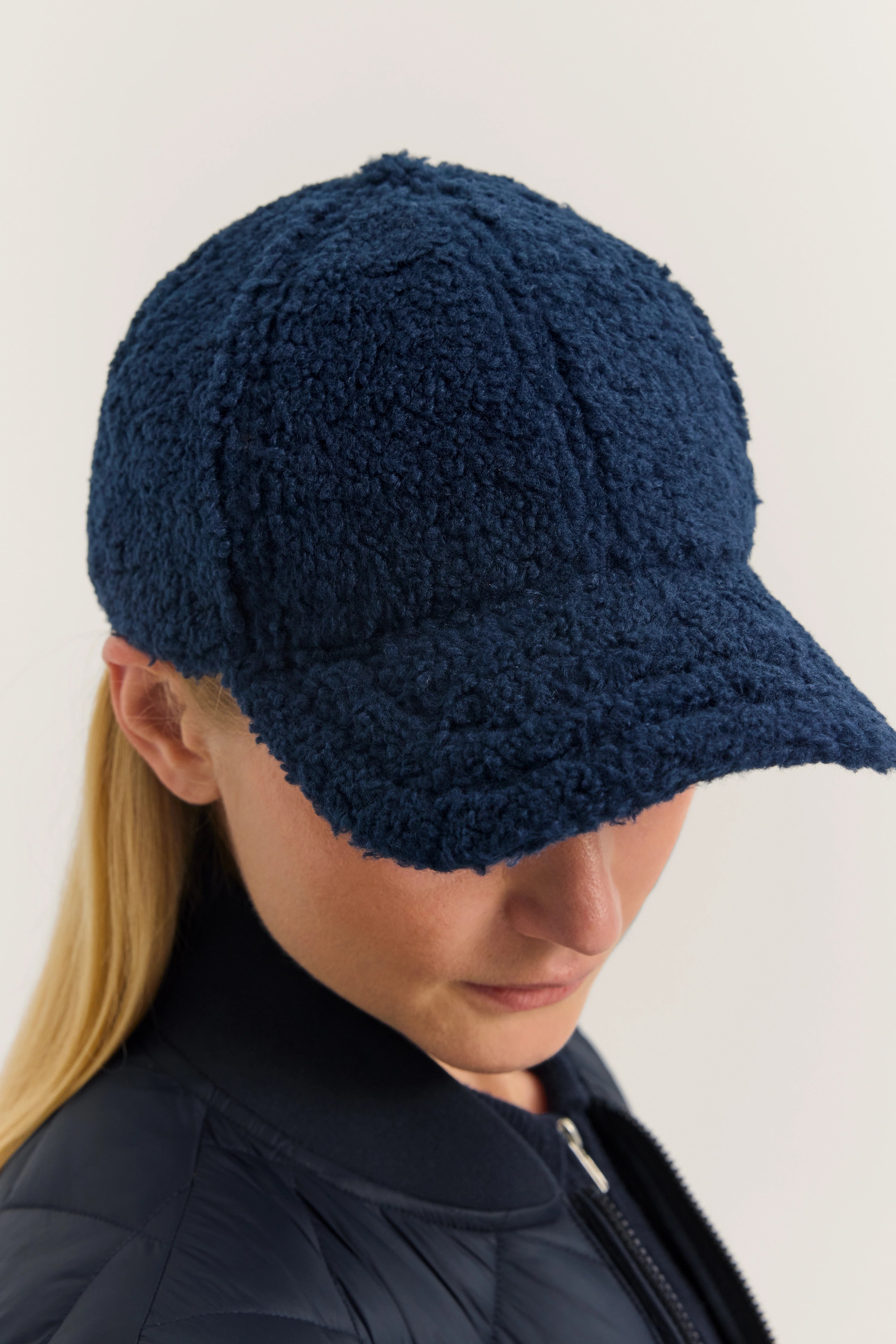 Dunkelblaue bugatti Kappe aus Fleece, getragen von Model in entspannter Pose, passend zur Steppjacke.