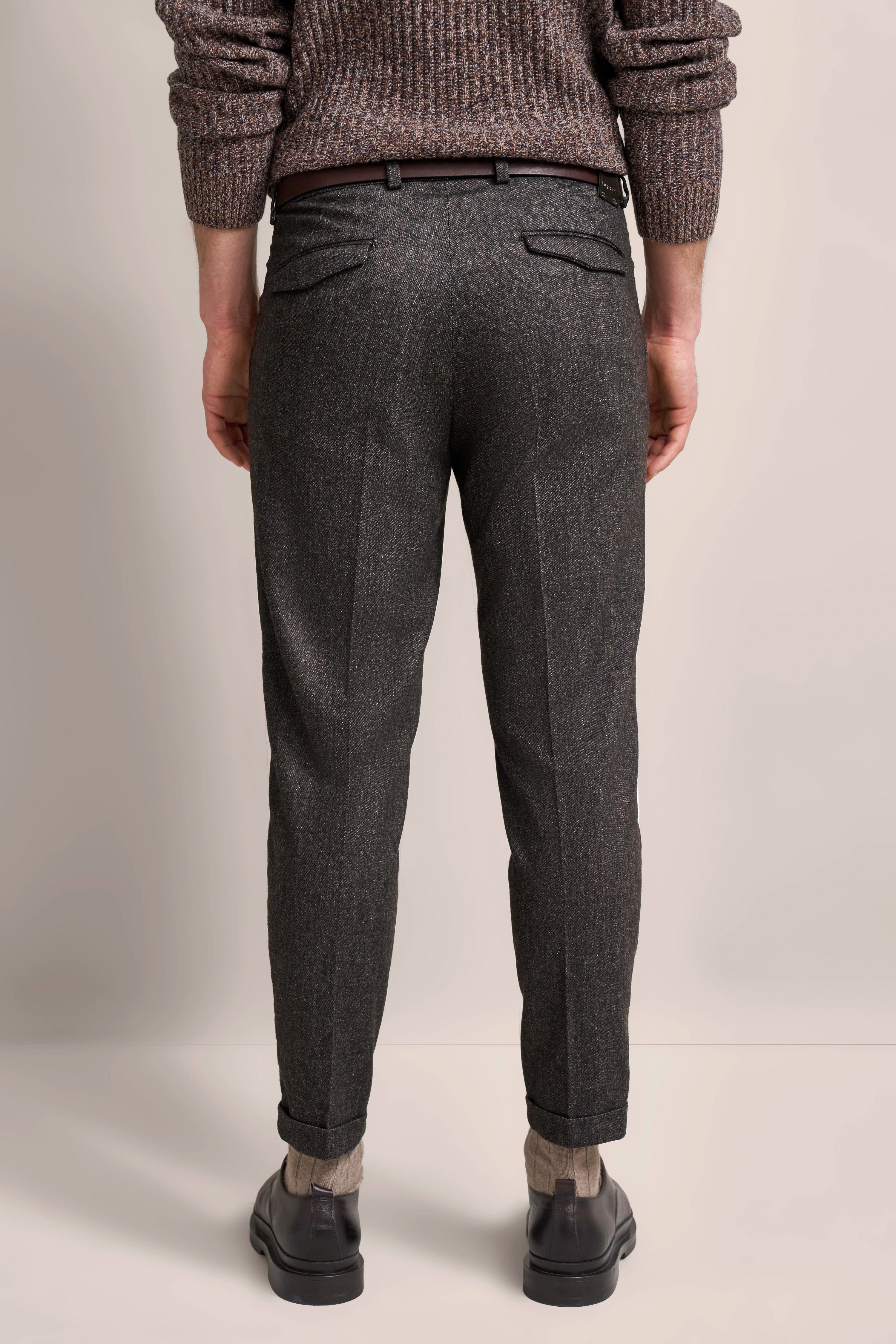 Grau melierte Hose mit braunem Gürtel und Strickpullover, Modelbild von hinten.
