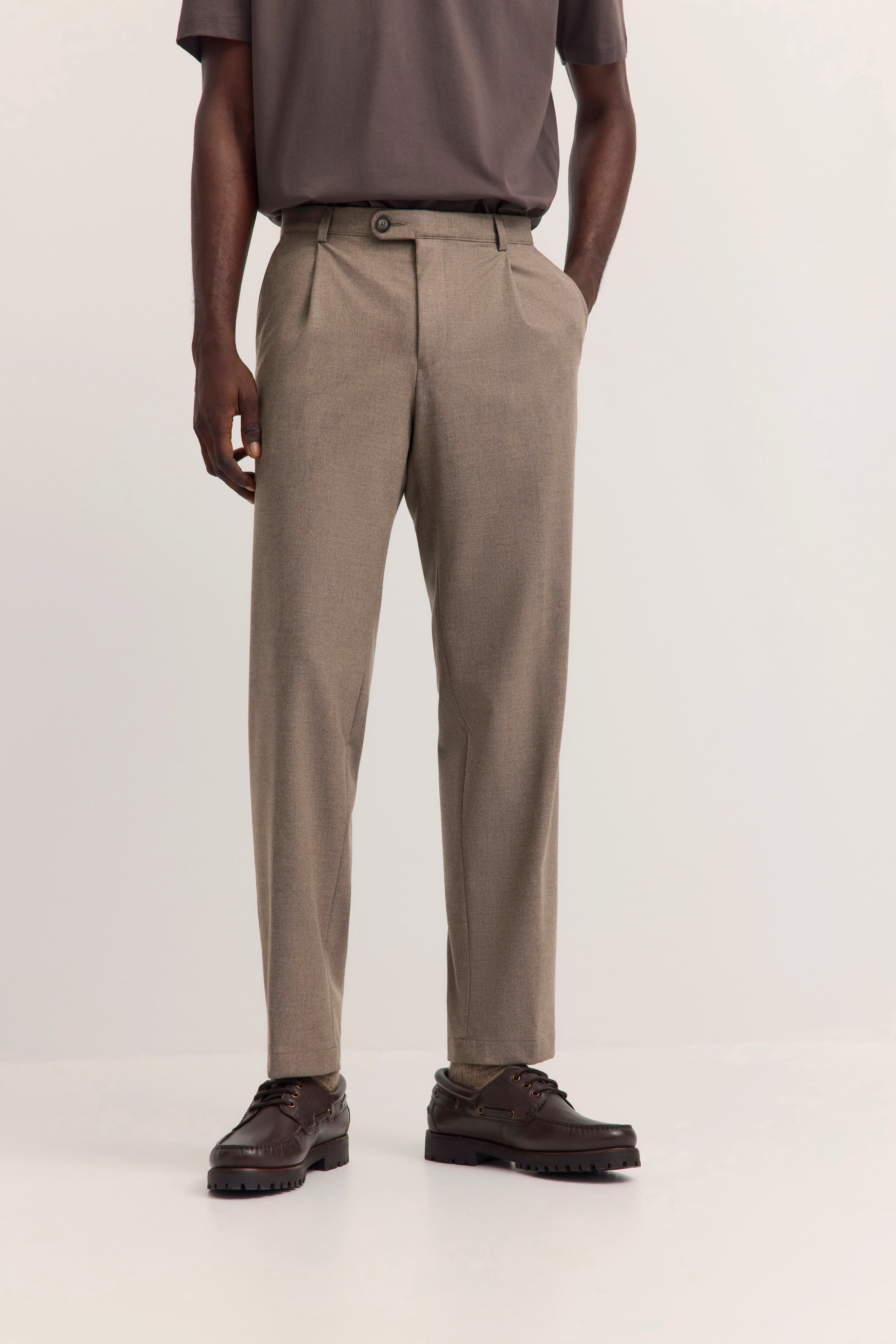 Beige bugatti Hose und braune Schuhe, legeres Modelbild mit Händen in den Taschen.