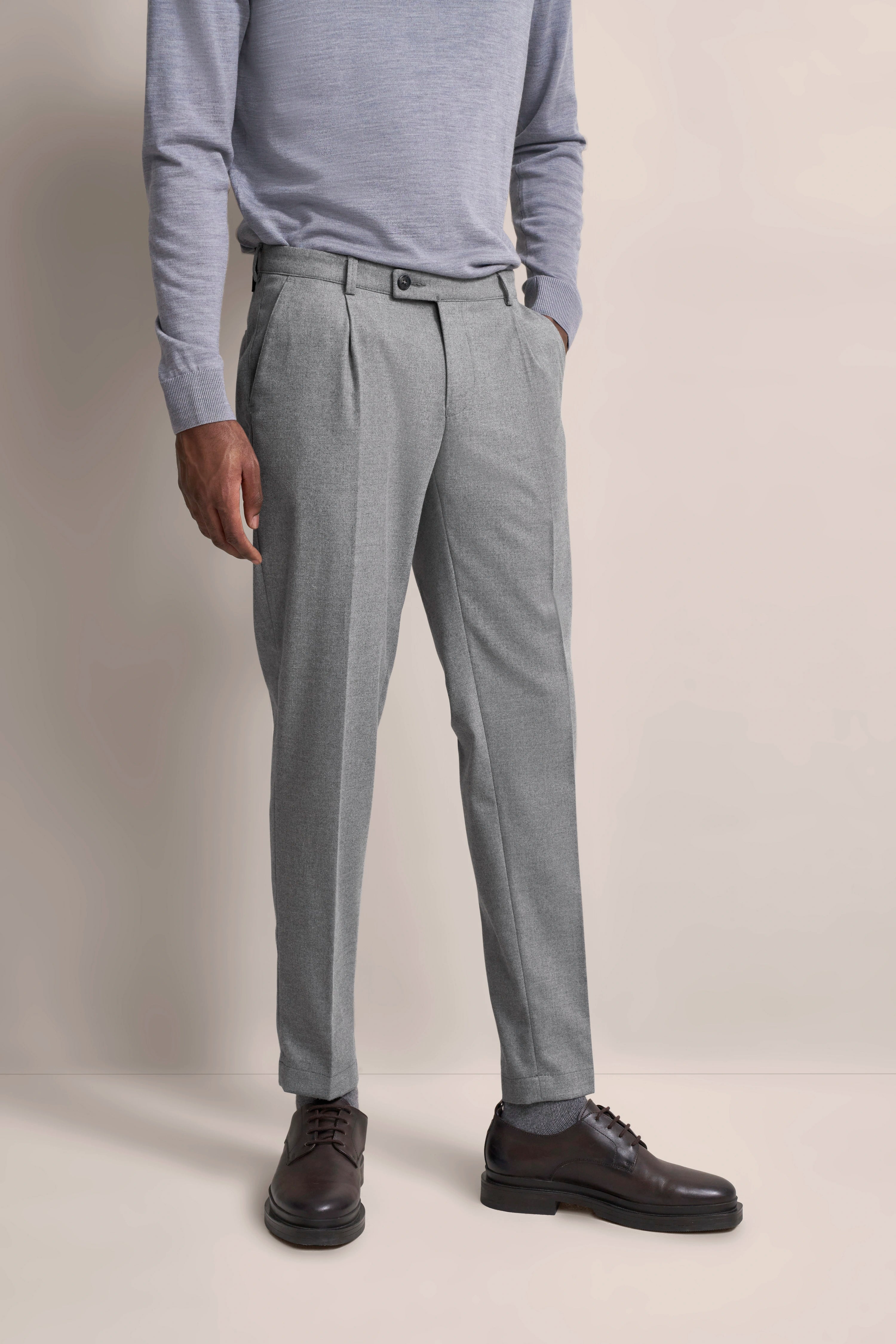 Grauer Anzughose mit Falten, lila Pullover, Modelbild ohne Kopf, lockere Pose, bugatti Stil.