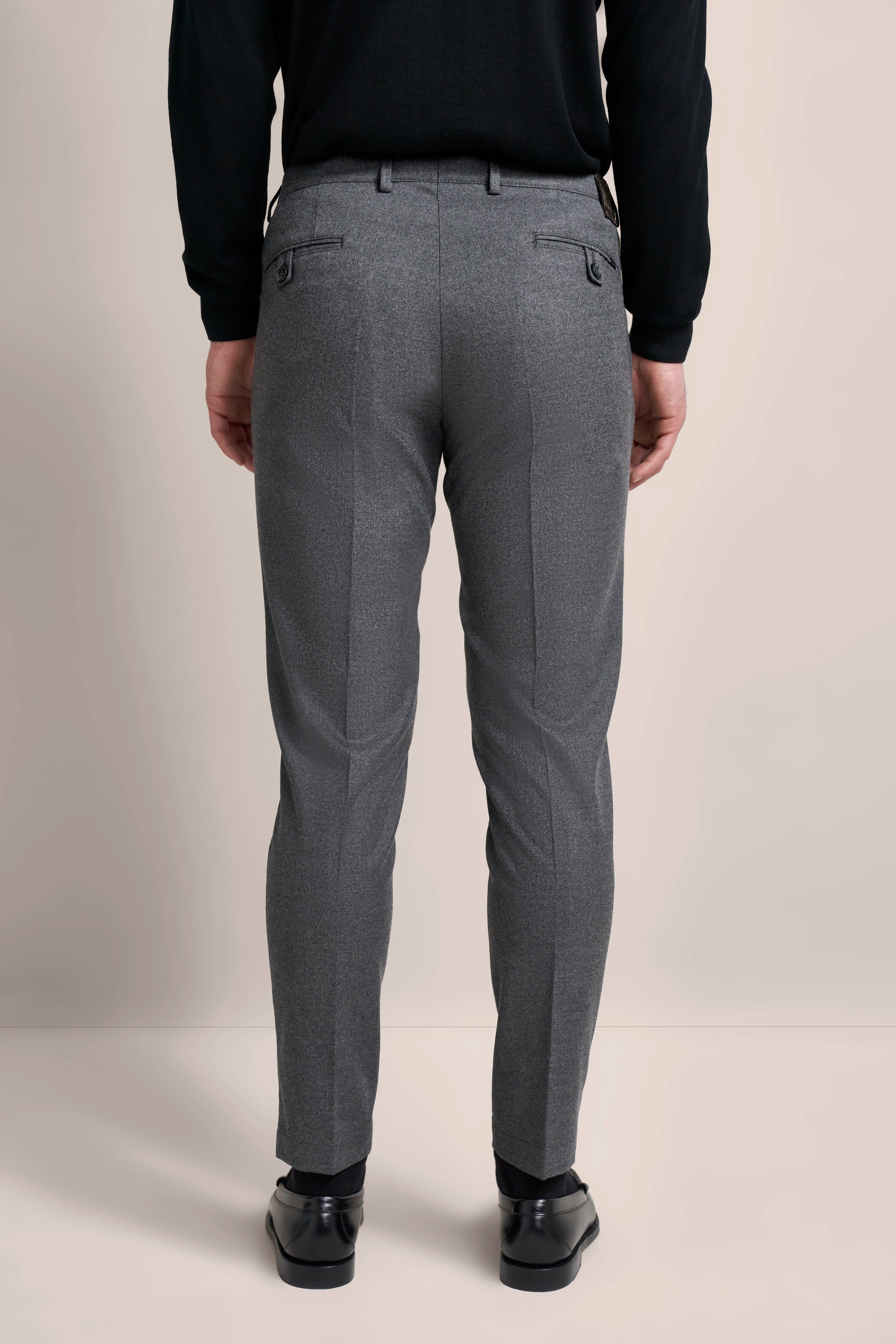 Graue Hose mit schwarzem Oberteil, Rückenansicht, legeres Modelbild von bugatti.