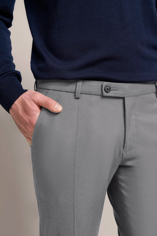 Dark blue sweater and gray pants, casual bust, hand in pocket.