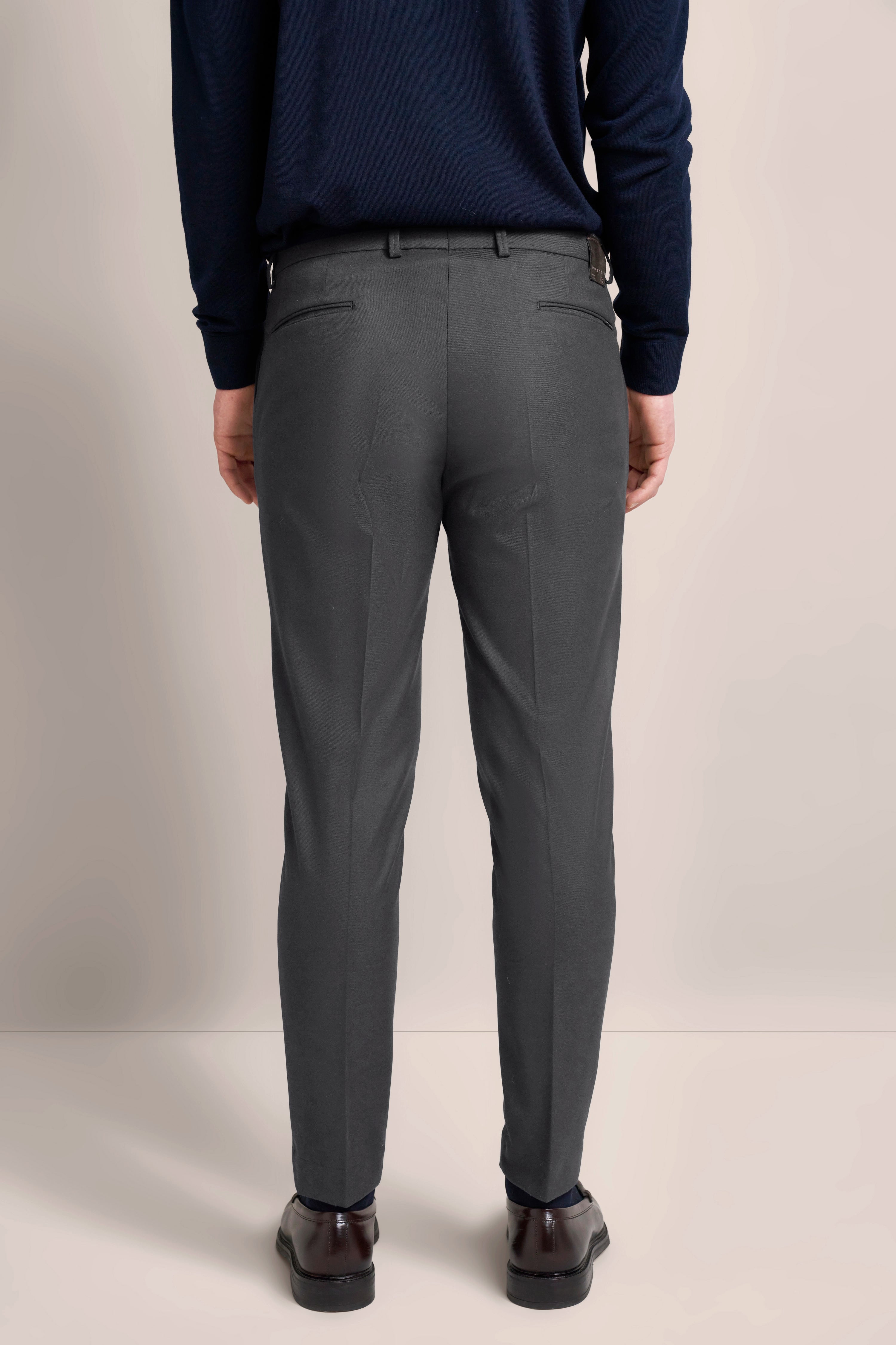 Elegant bugatti outfit: Dark blue sweater, gray pants, model rear view.