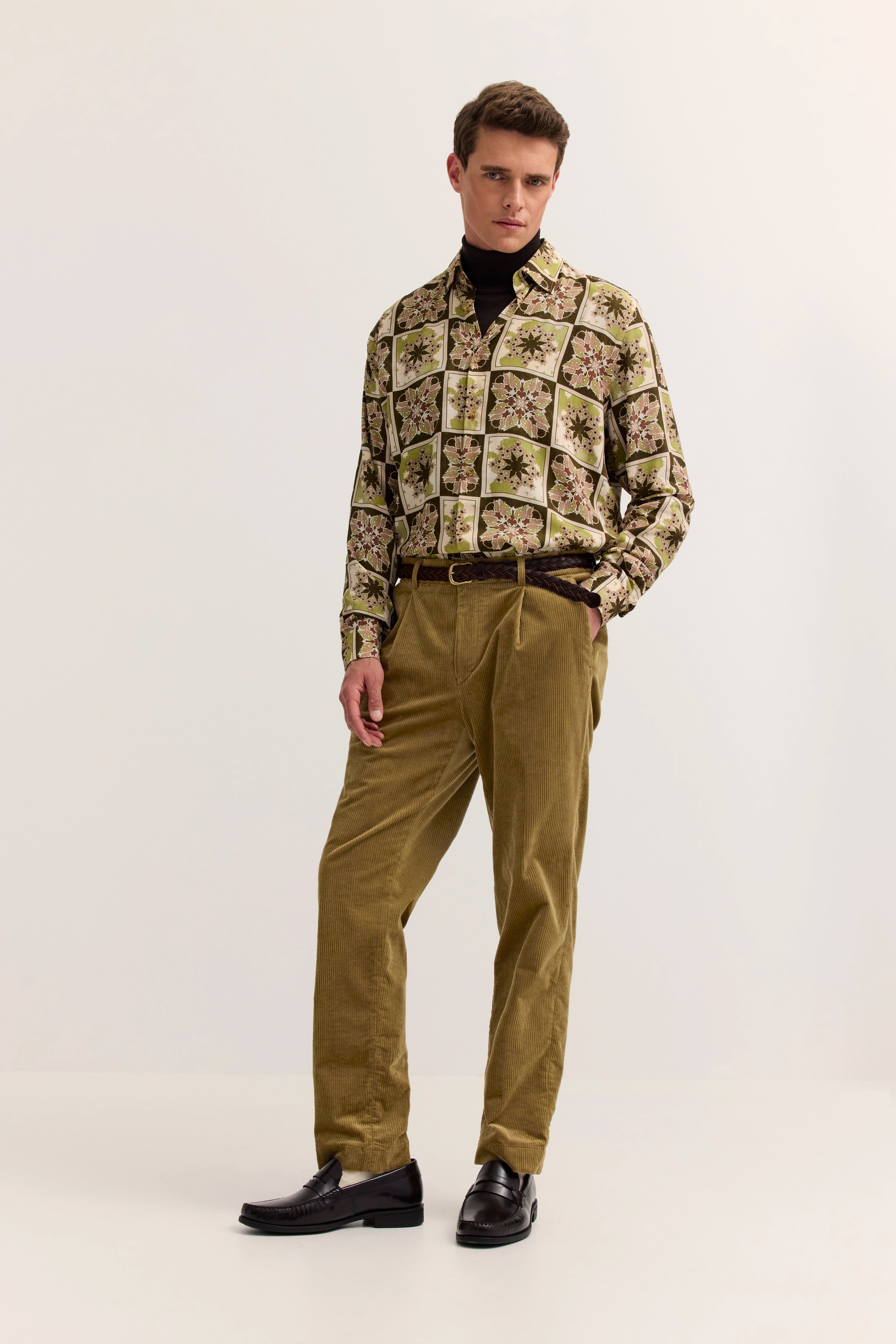 Nahaufnahme von olivgrüner Cordhose und gemustertem Hemd mit geflochtenem Gürtel, bugatti Stil.