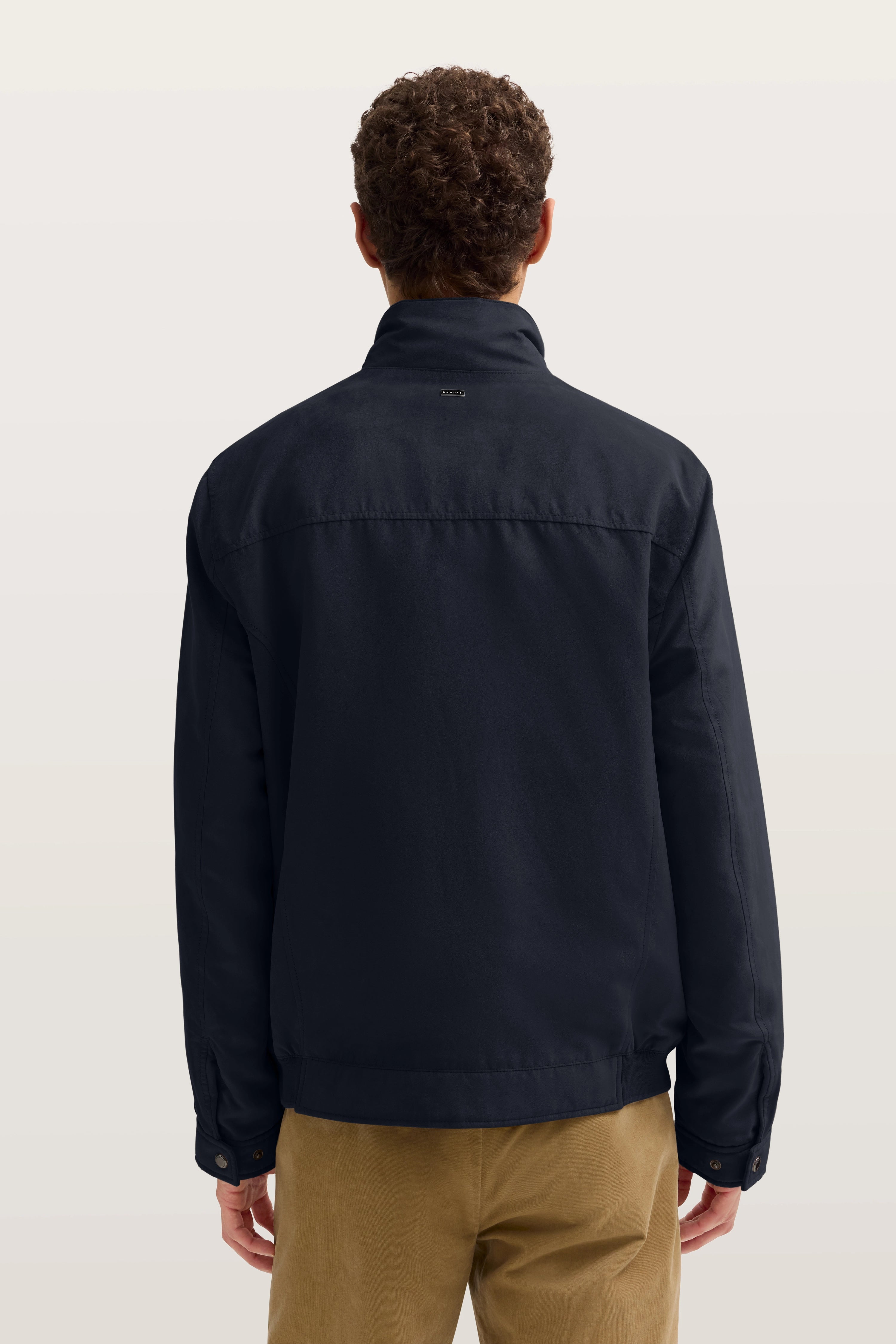 Herrenjacke von bugatti in Dunkelblau von hinten, getragen von einem Model, lässige Pose.