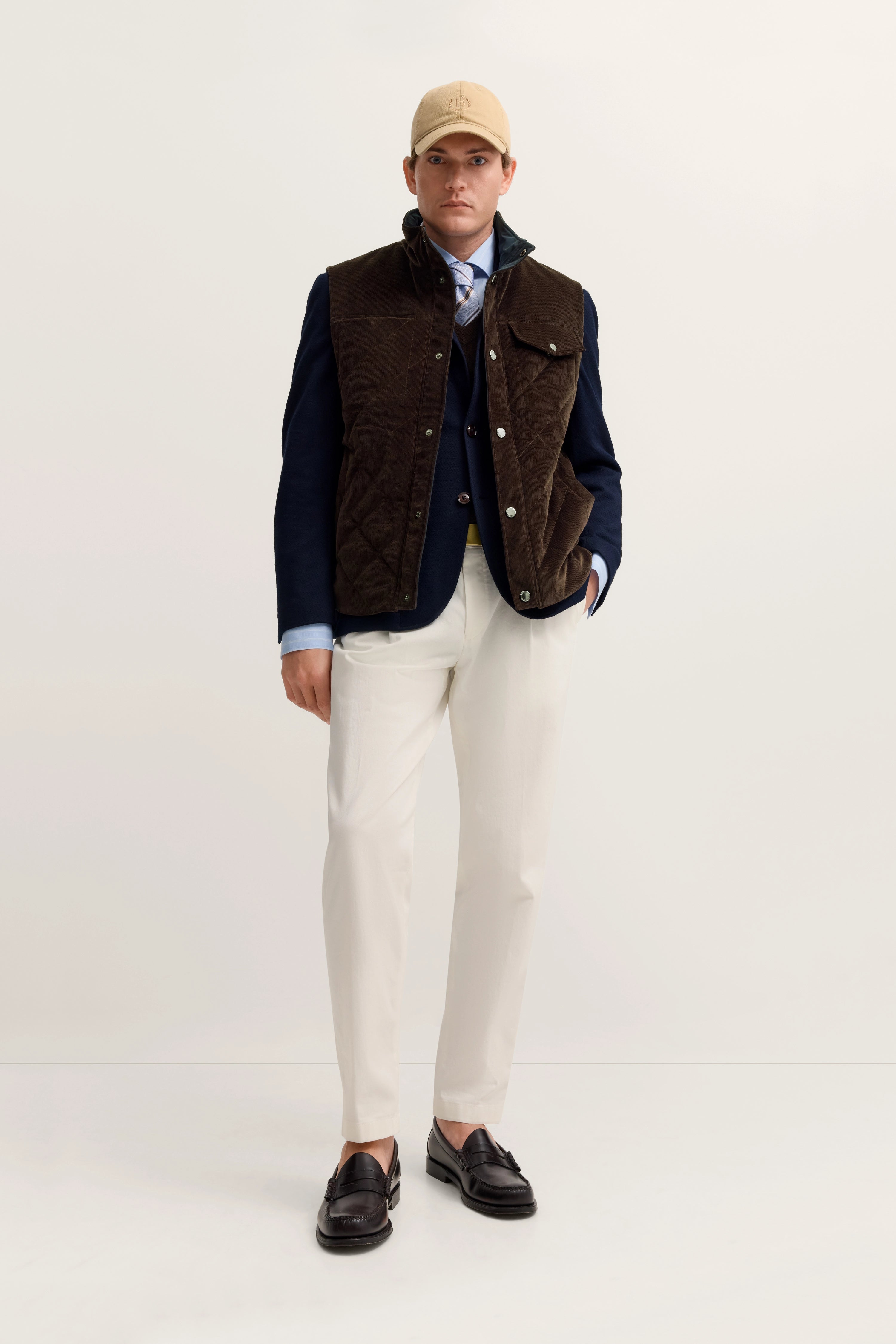 Model trägt braune Weste, dunkelblauen Blazer, hellblaue Hemd, beige Hose