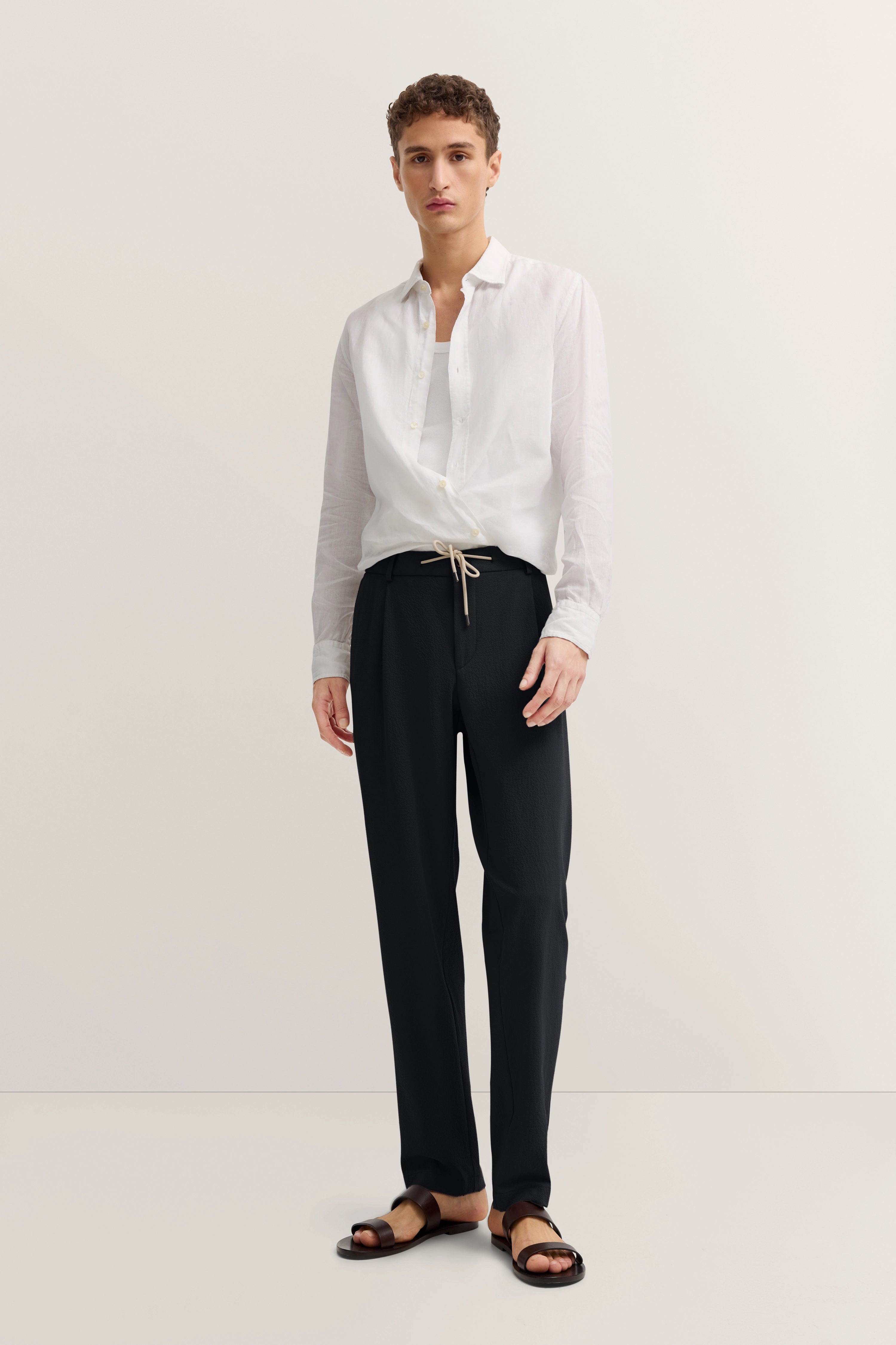 Weißes Hemd, schwarze Hose, Modelbild, lässige Pose, bugatti Stil und Eleganz.