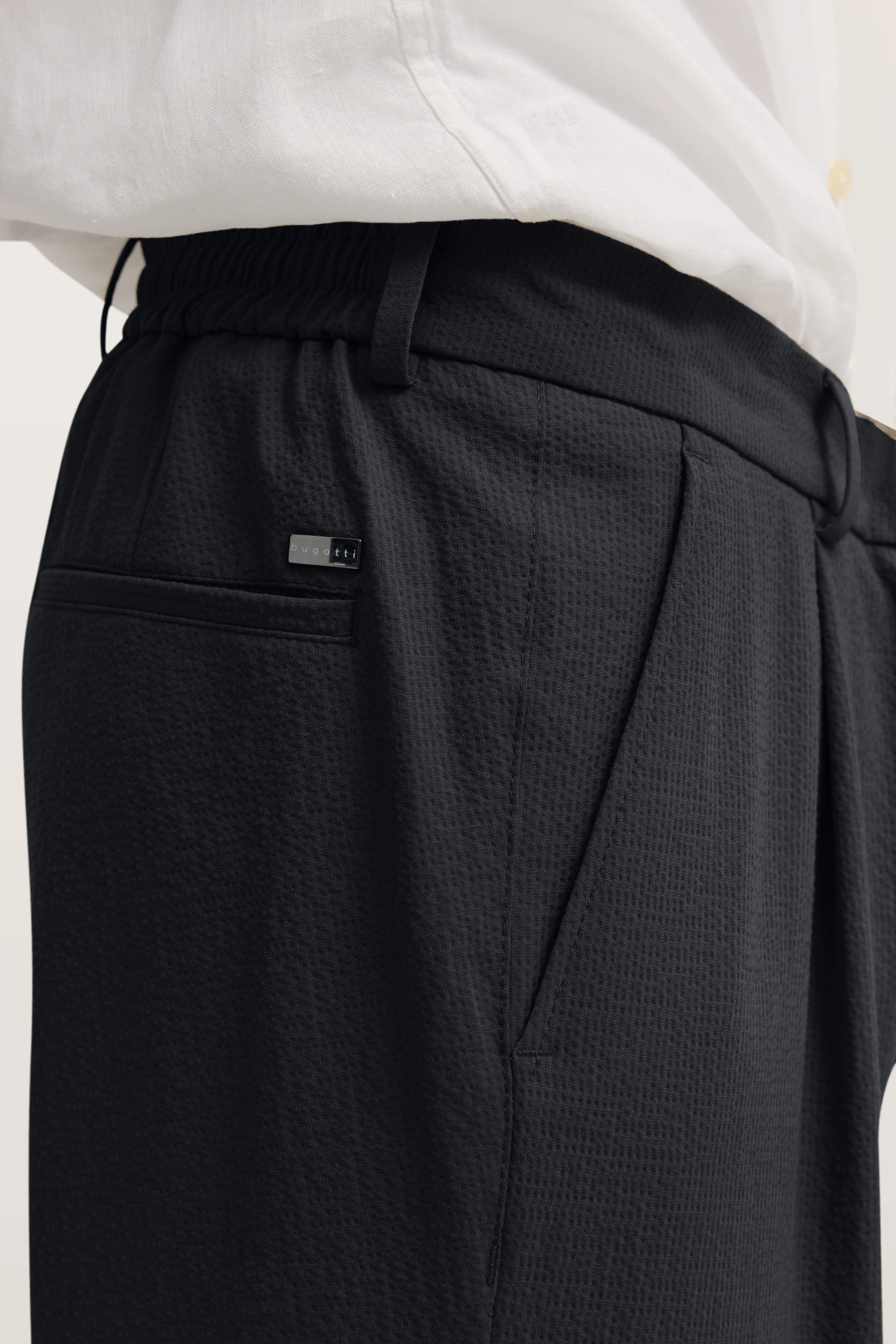 Schwarze bugatti Hose, Textur-Detail, legeres Bild, kombiniert mit weißem Hemd.