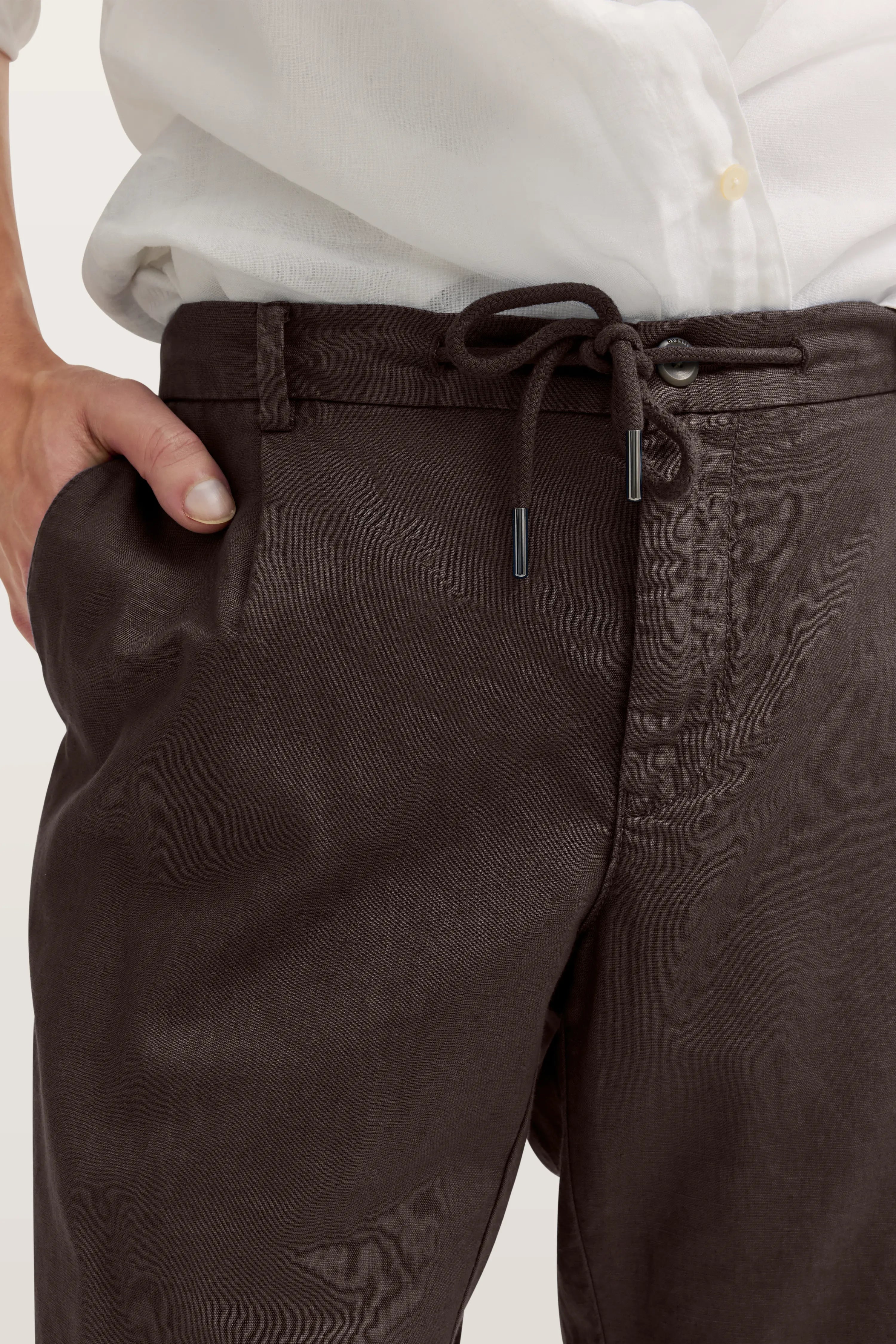 Braune Hose mit Kordelzug, Büstenbild, kombiniert mit weißem Hemd, entspannter Stil von bugatti.