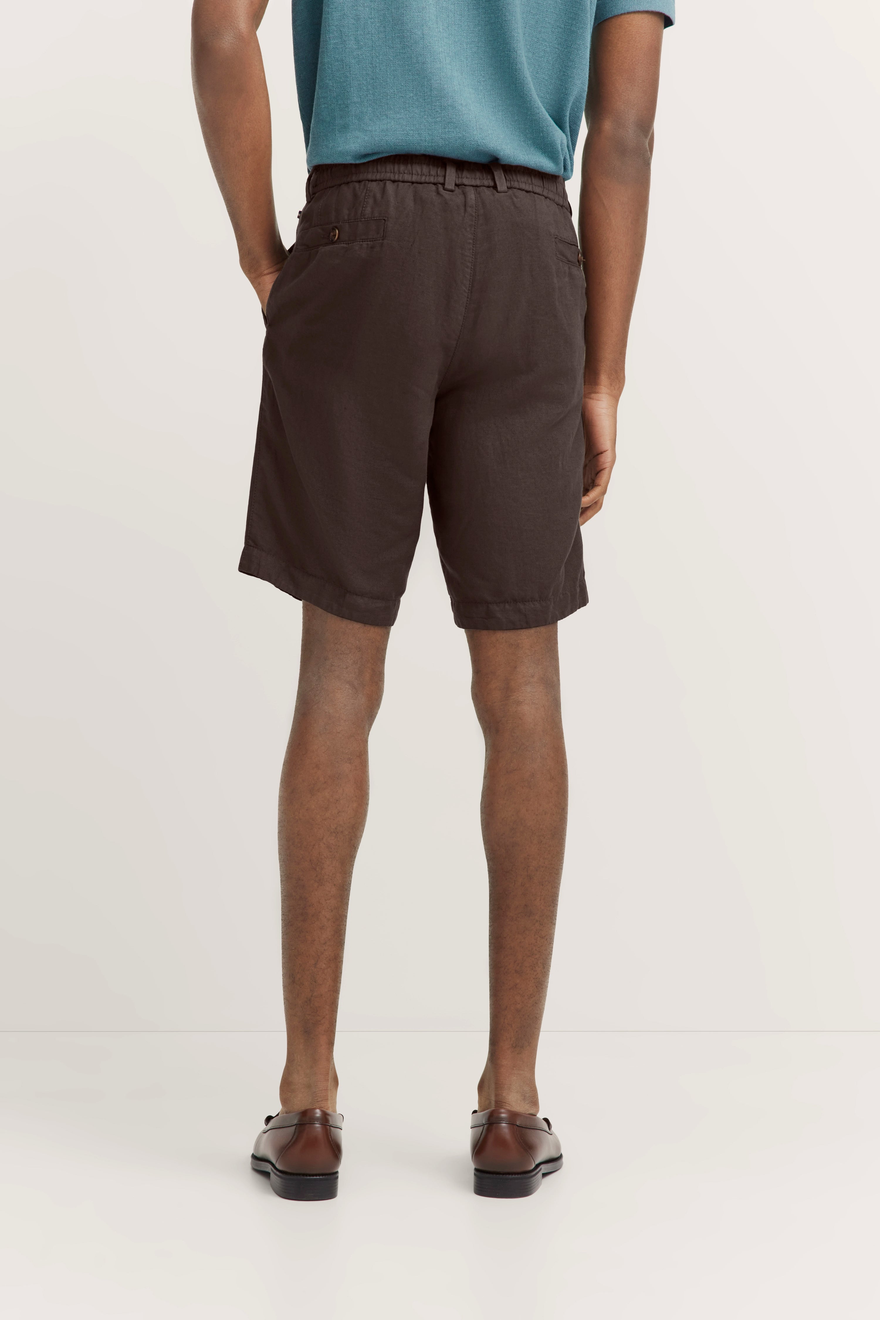 Rückansicht eines Models in braunen Shorts und blauen Shirt von bugatti, legerer Stil.