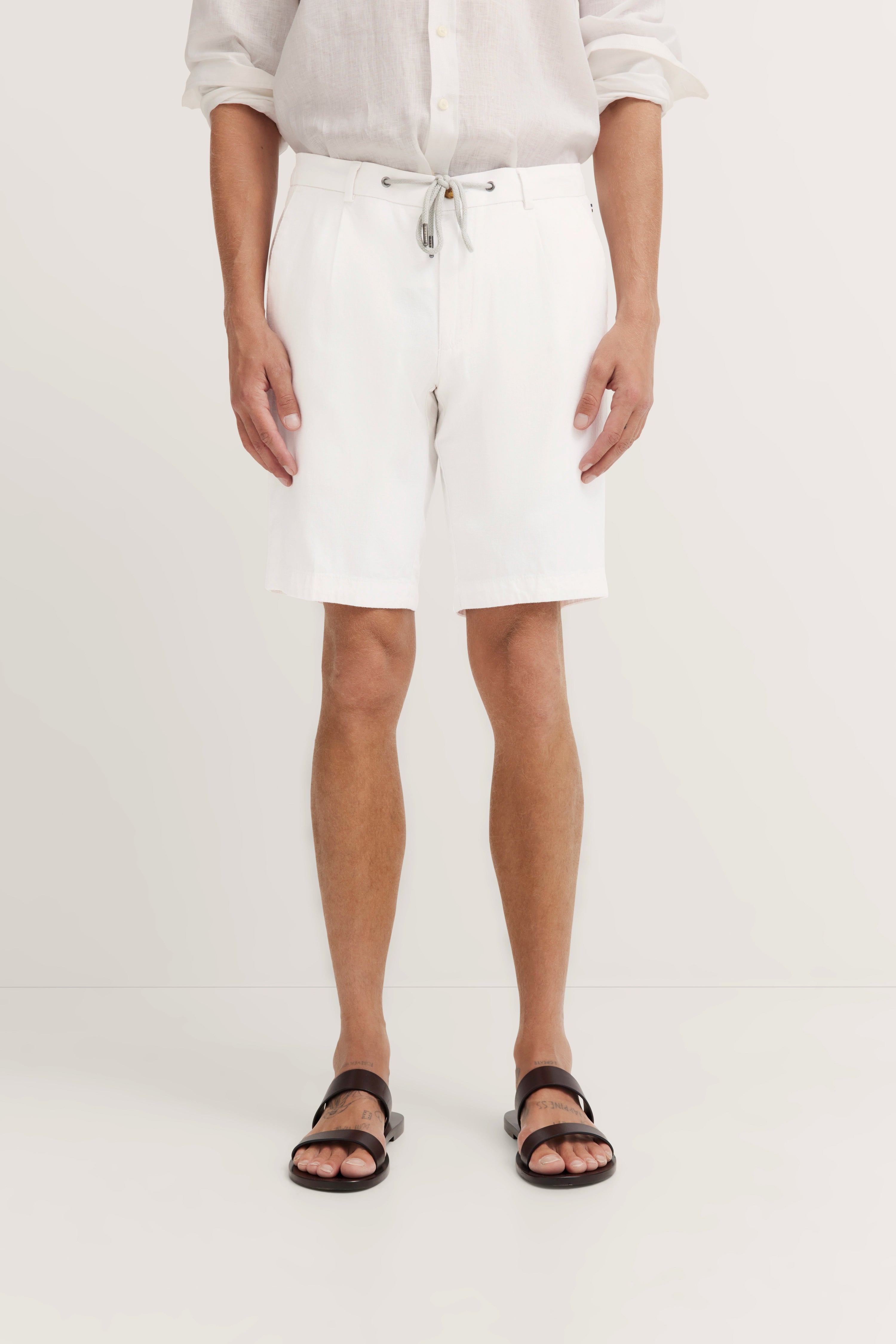 Weißes Outfit mit Hemd und Shorts, legeres Modelbild, entspannte Pose, bugatti Stil.
