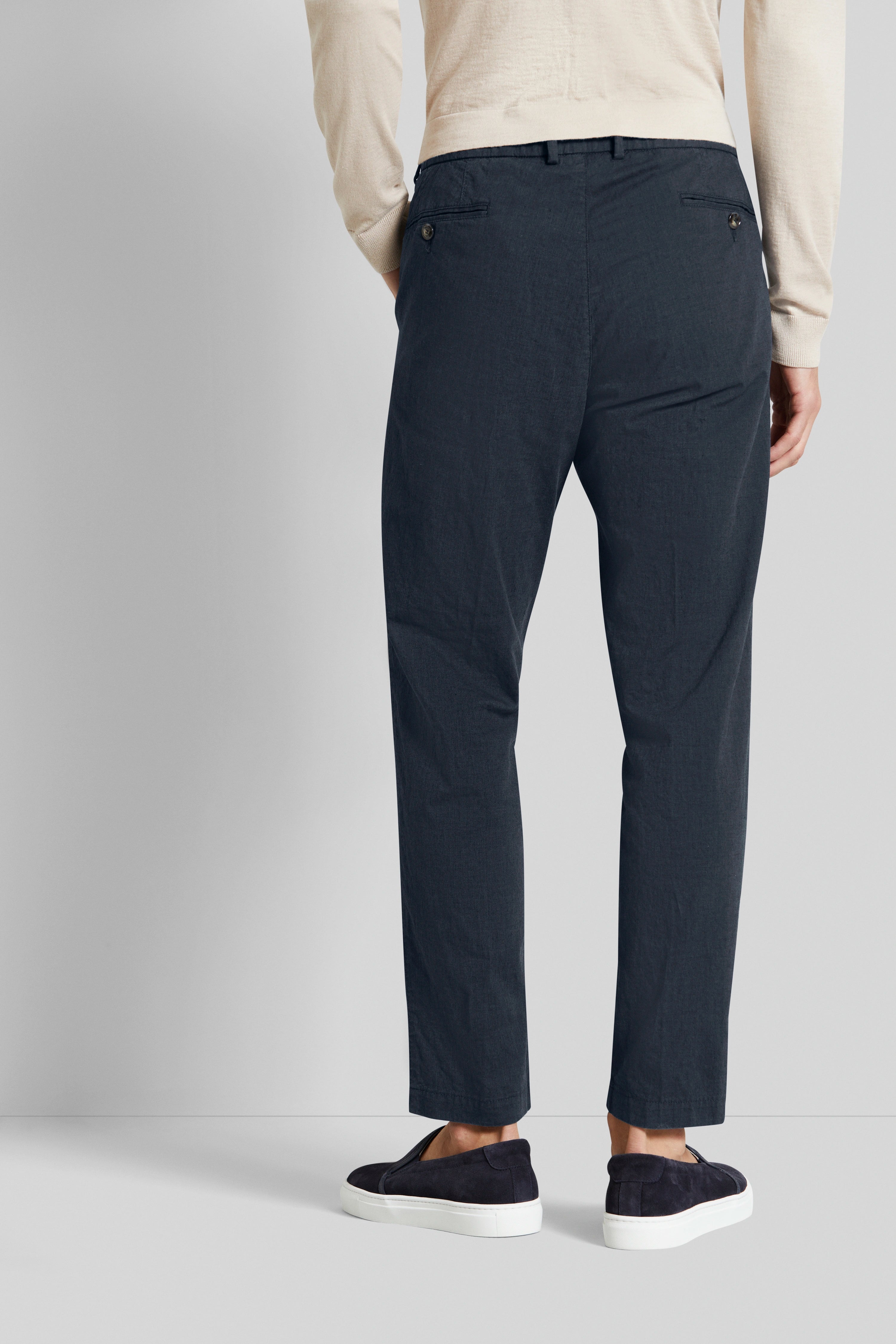 Beige trui, donkerblauwe broek, model van achteren, ontspannen pose, bugatti stijl en elegantie.