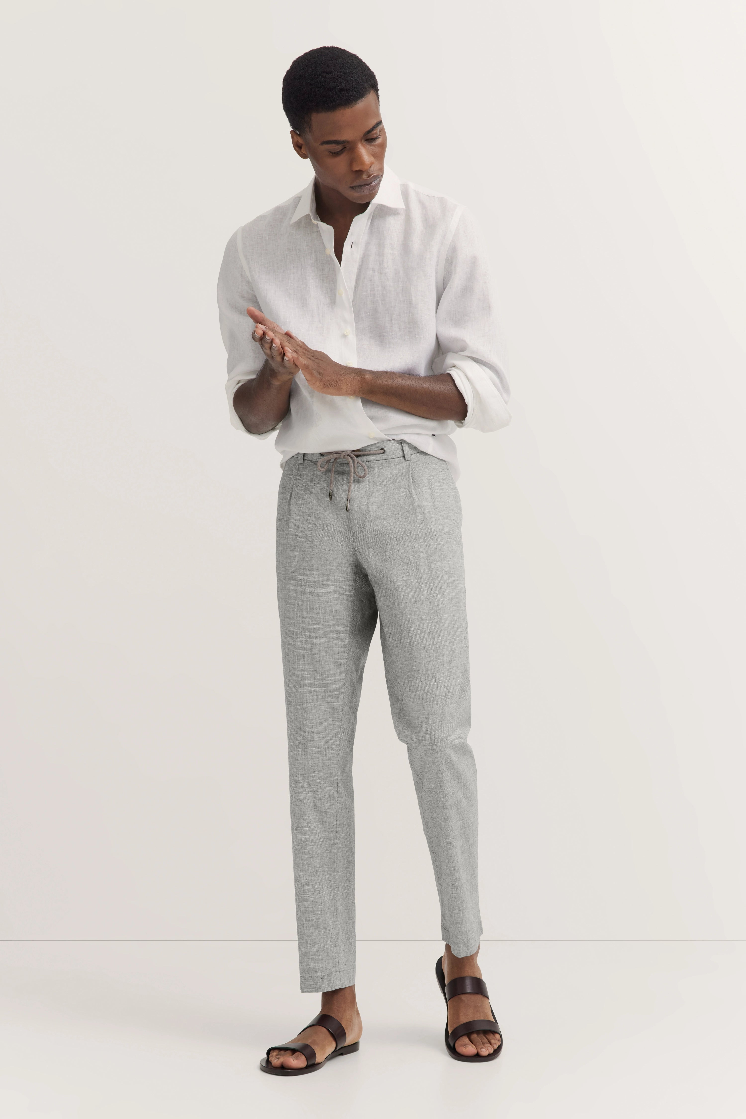 Wit overhemd, grijze broek, model poseert ontspannen, bugatti stijl.