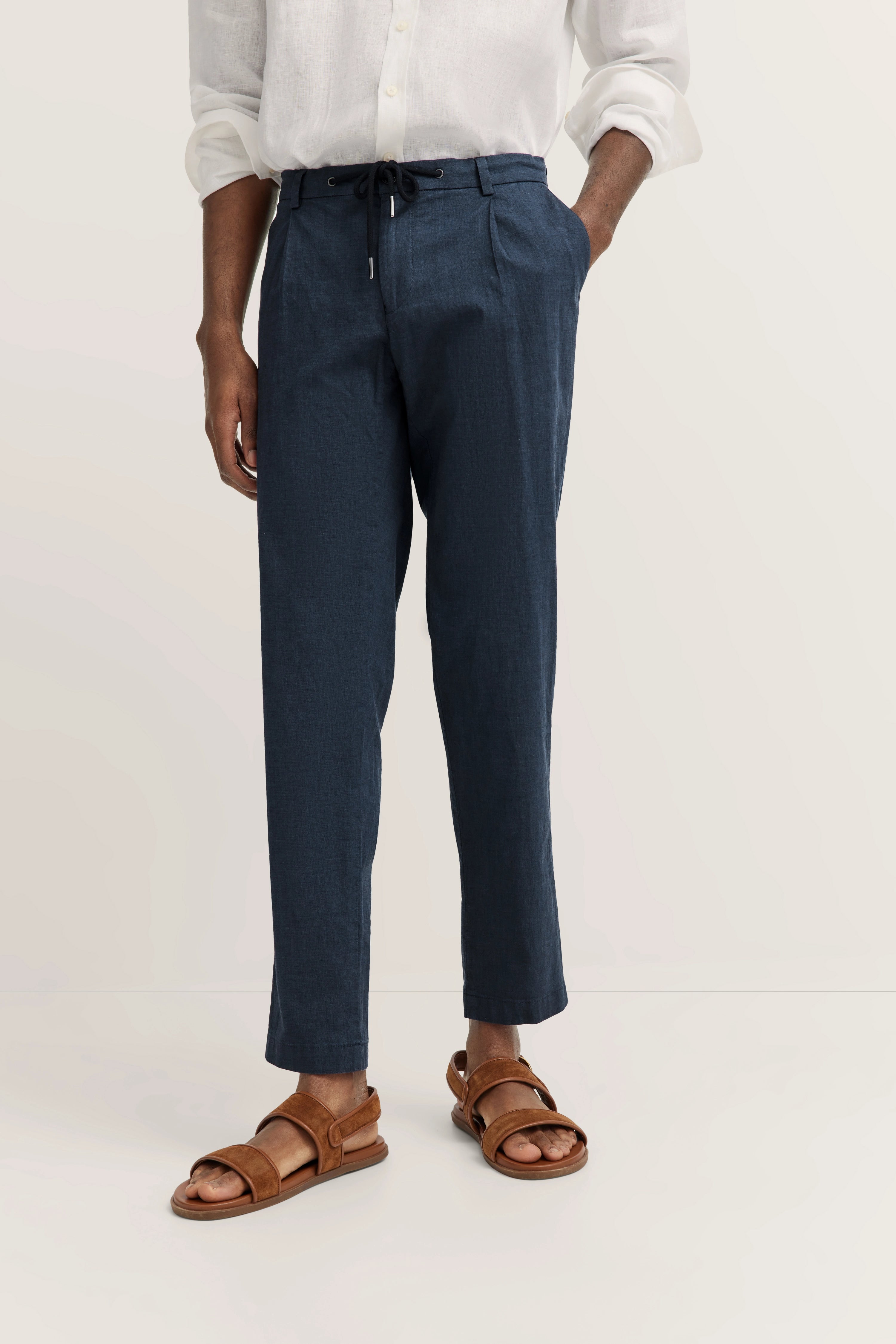 Wit linnen overhemd en marineblauwe broek, casual modelpose, ontspannen uitstraling.