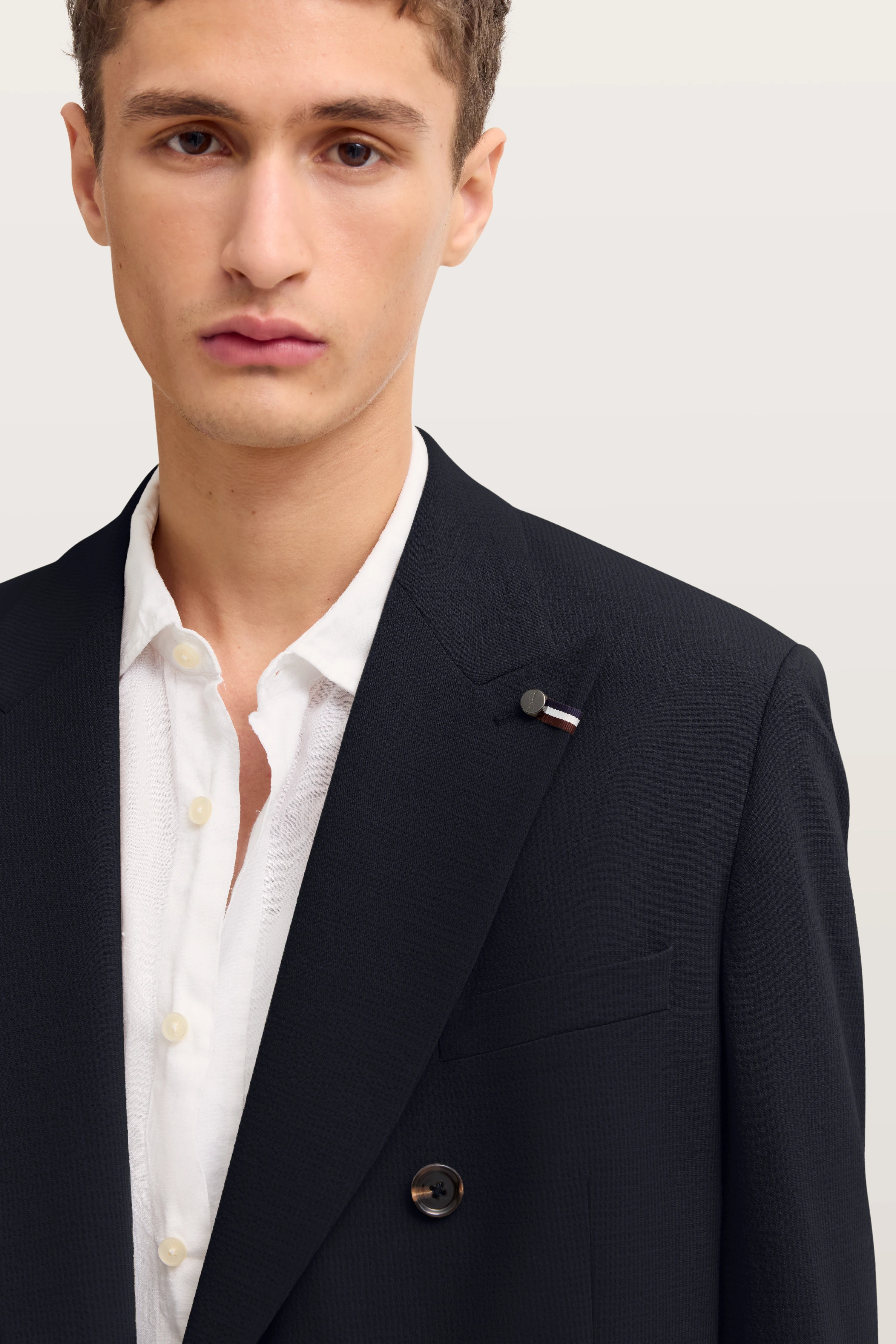 Bugatti Modelbild: Schwarzes Sakko, weißes Hemd, legeres Posing, zeitlose Eleganz.