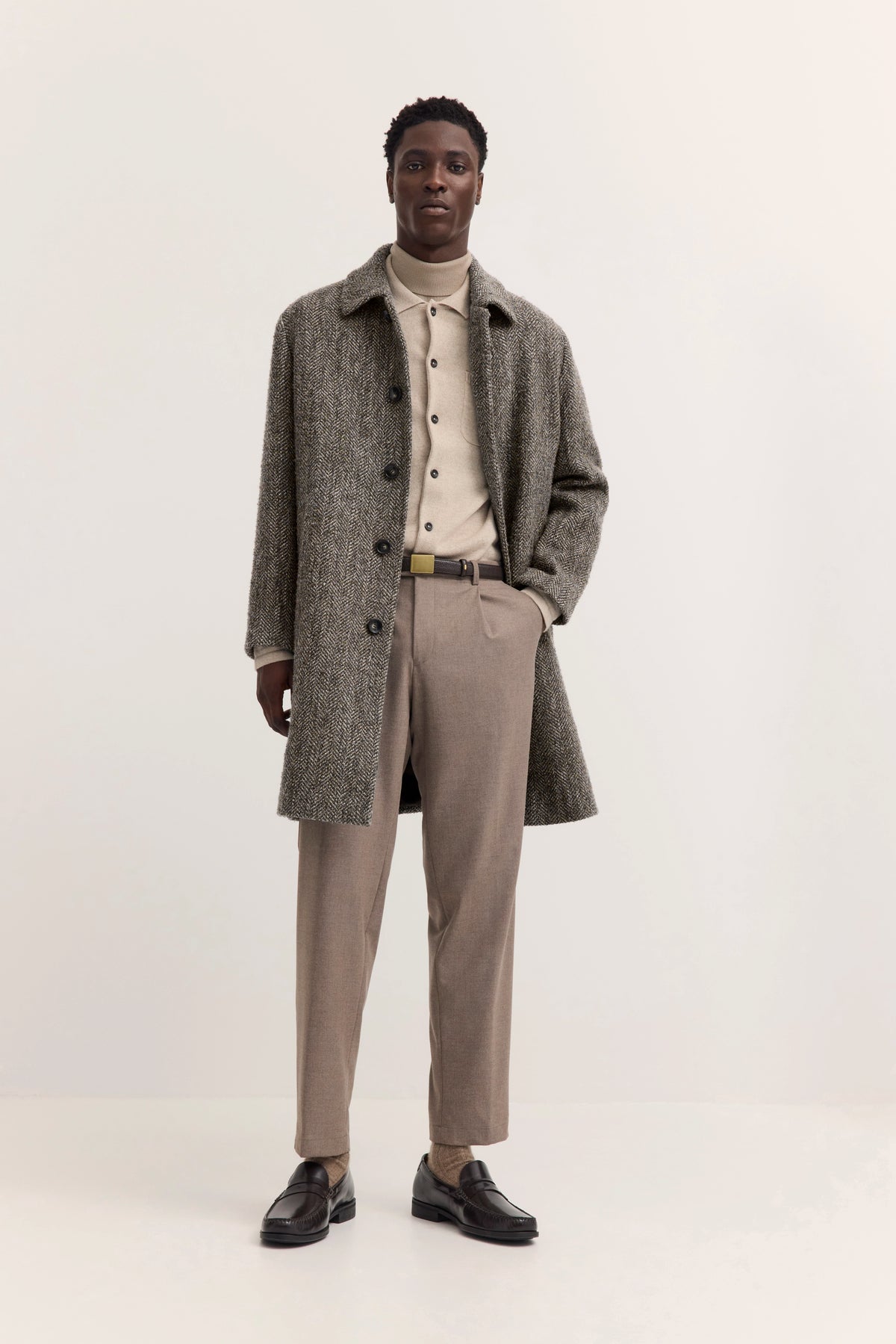 Grauer Fischgrätenmantel und beige Rollkragen auf Büstenbild von bugatti.