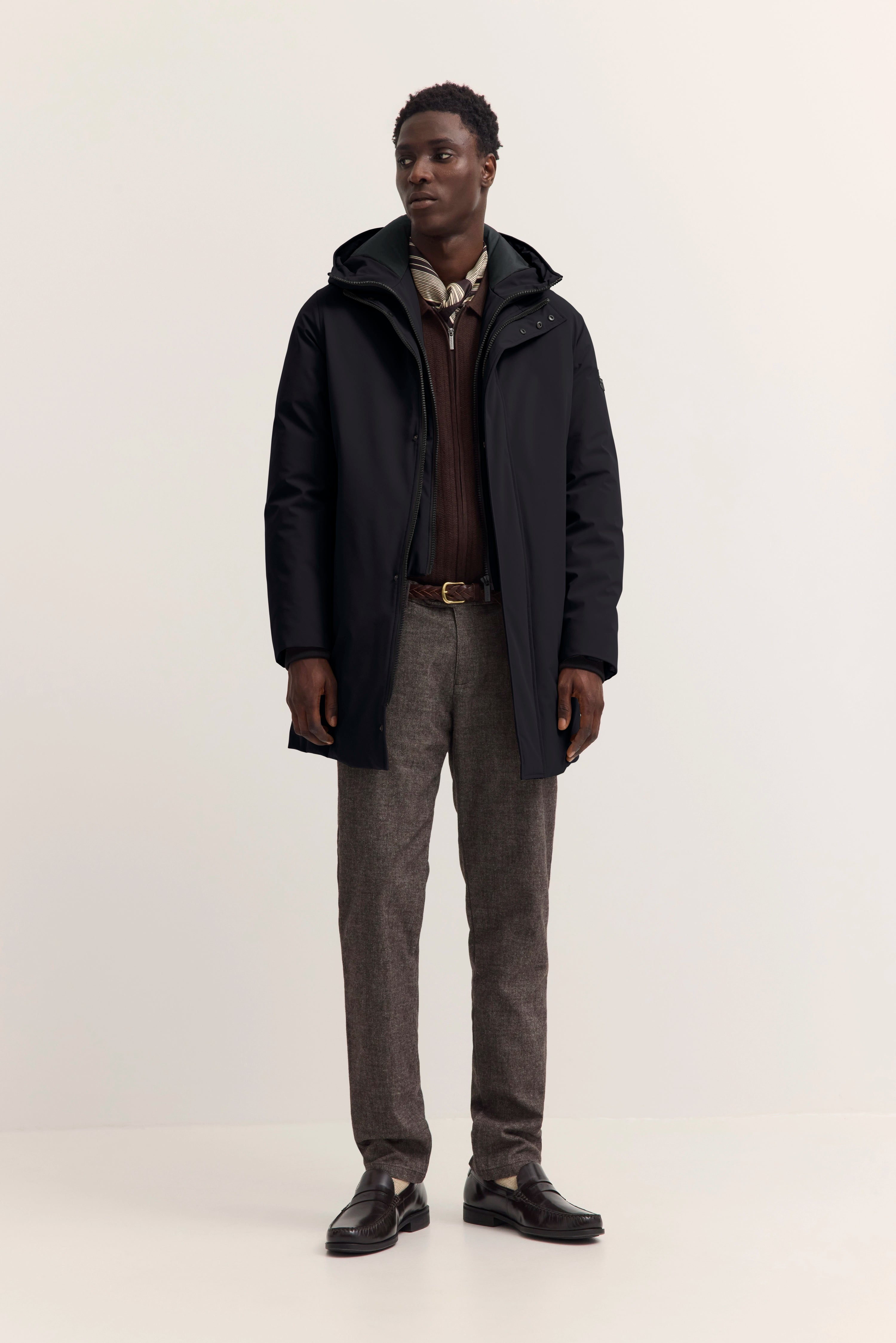 bugatti Model in schwarzem Mantel, braunem Pullover, grauer Hose