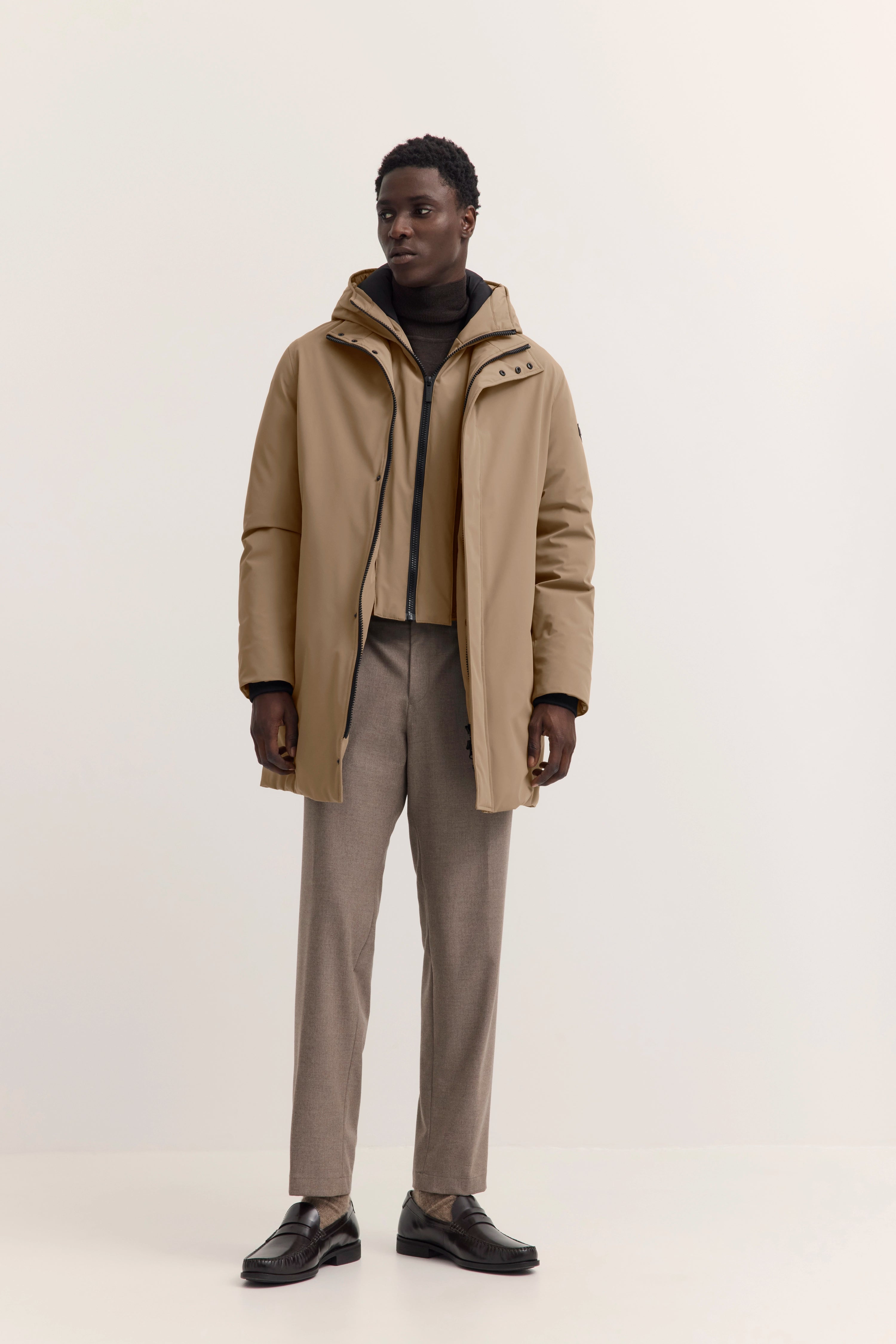 Beiger bugatti Parka, dunkler Rollkragenpullover, beige Hose, schwarzer Loafer