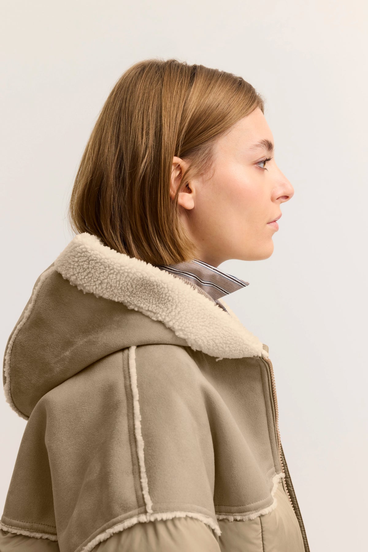 Seitenansicht einer Frau im beigen bugatti Parka mit Schafsfellkragen, legeres Modelbild.
