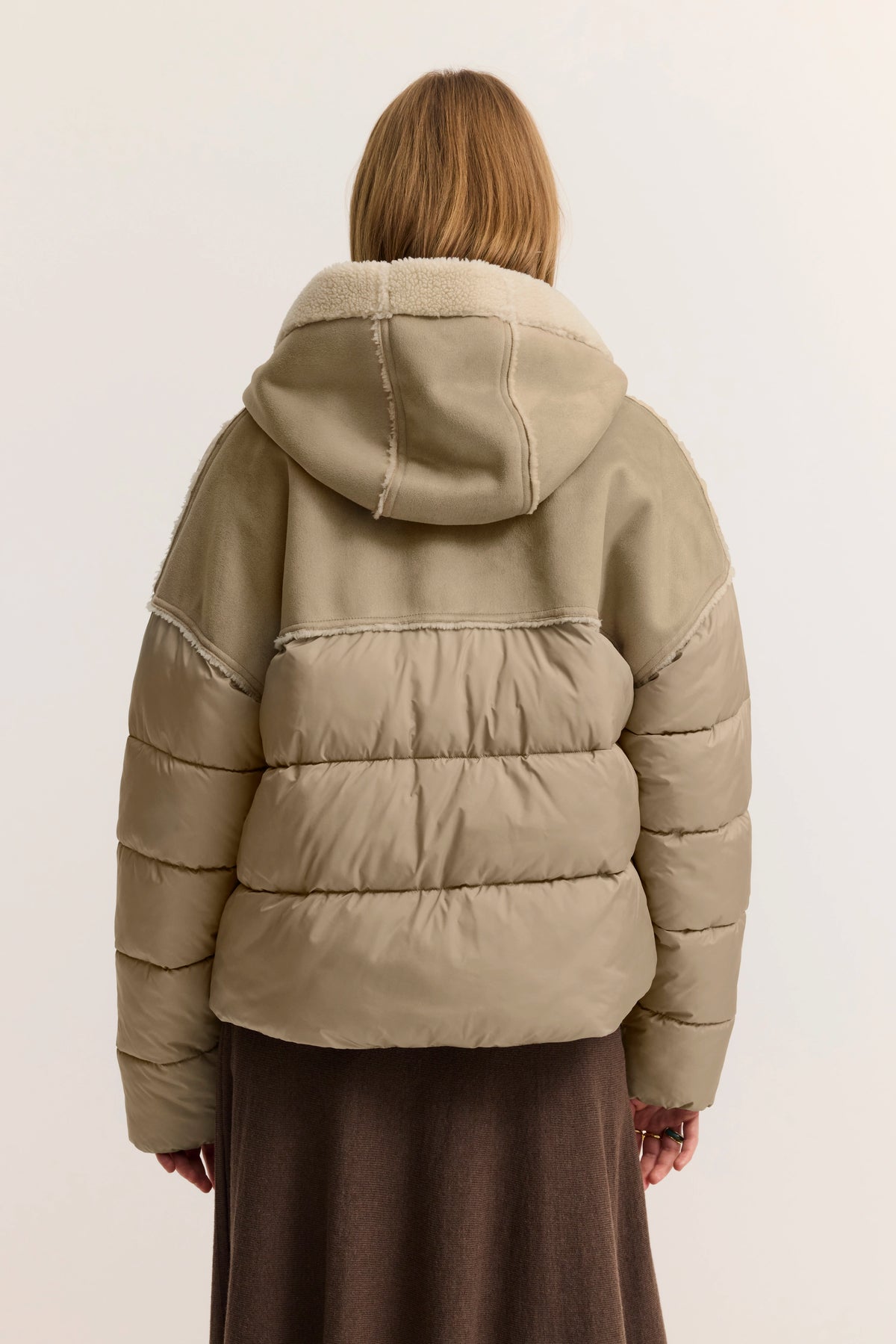 Beige Steppjacke mit Kapuze, Model von hinten. Urbaner, entspannter Look von bugatti.