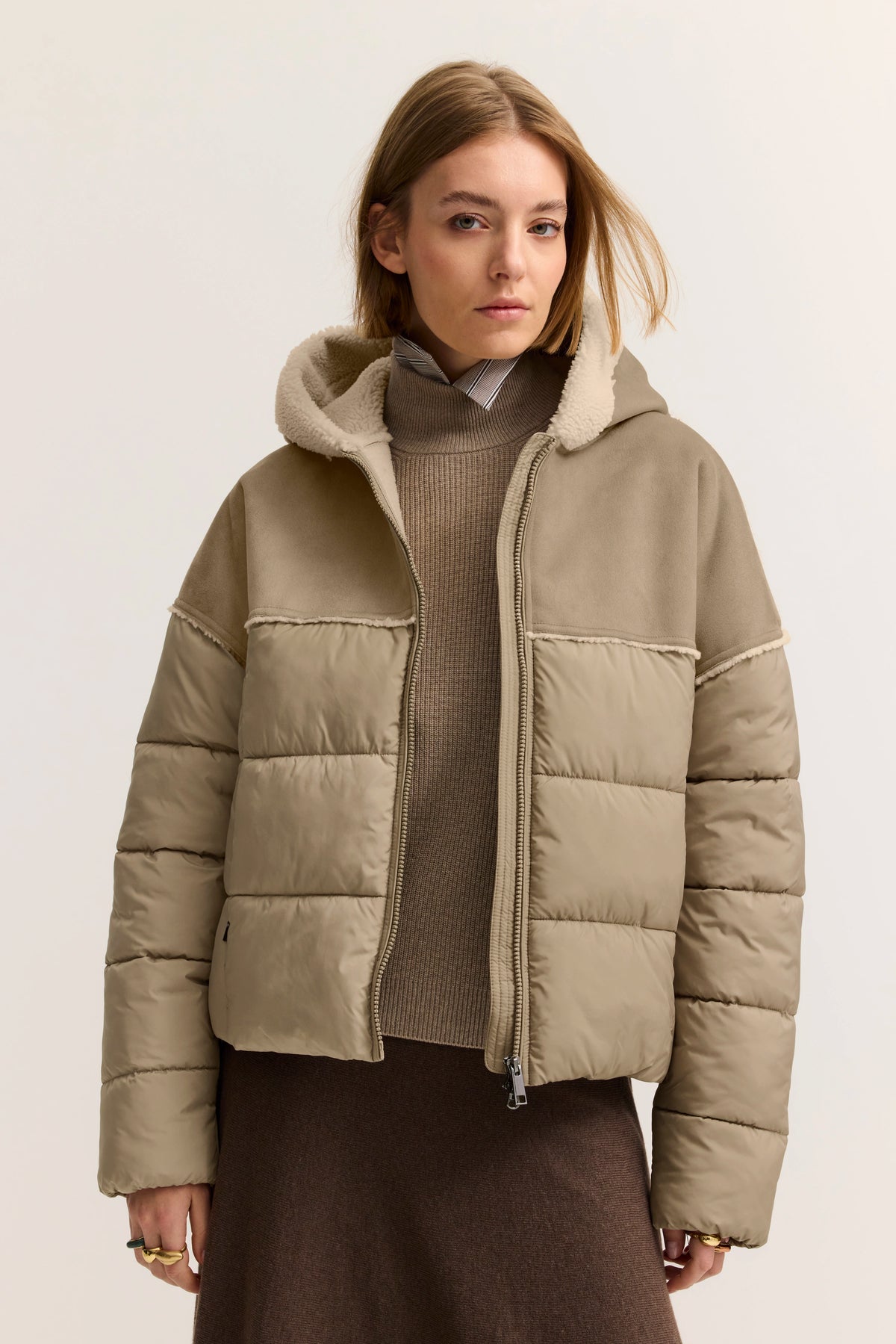 Model mit beigefarbener bugatti Daunenjacke, Kapuze und braunem Rollkragen, lässig und stilvoll.