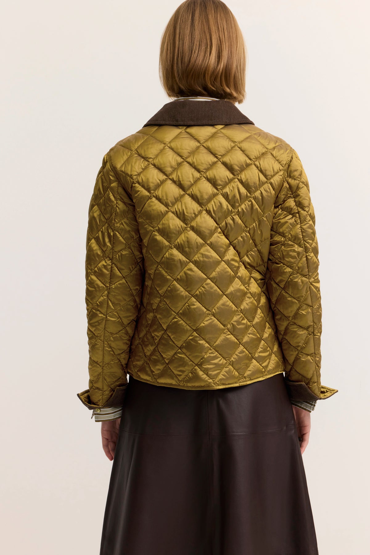Steppjacke in Olivgrün, Rückansicht, mit einem braunen Rock kombiniert, legeres Modelbild.