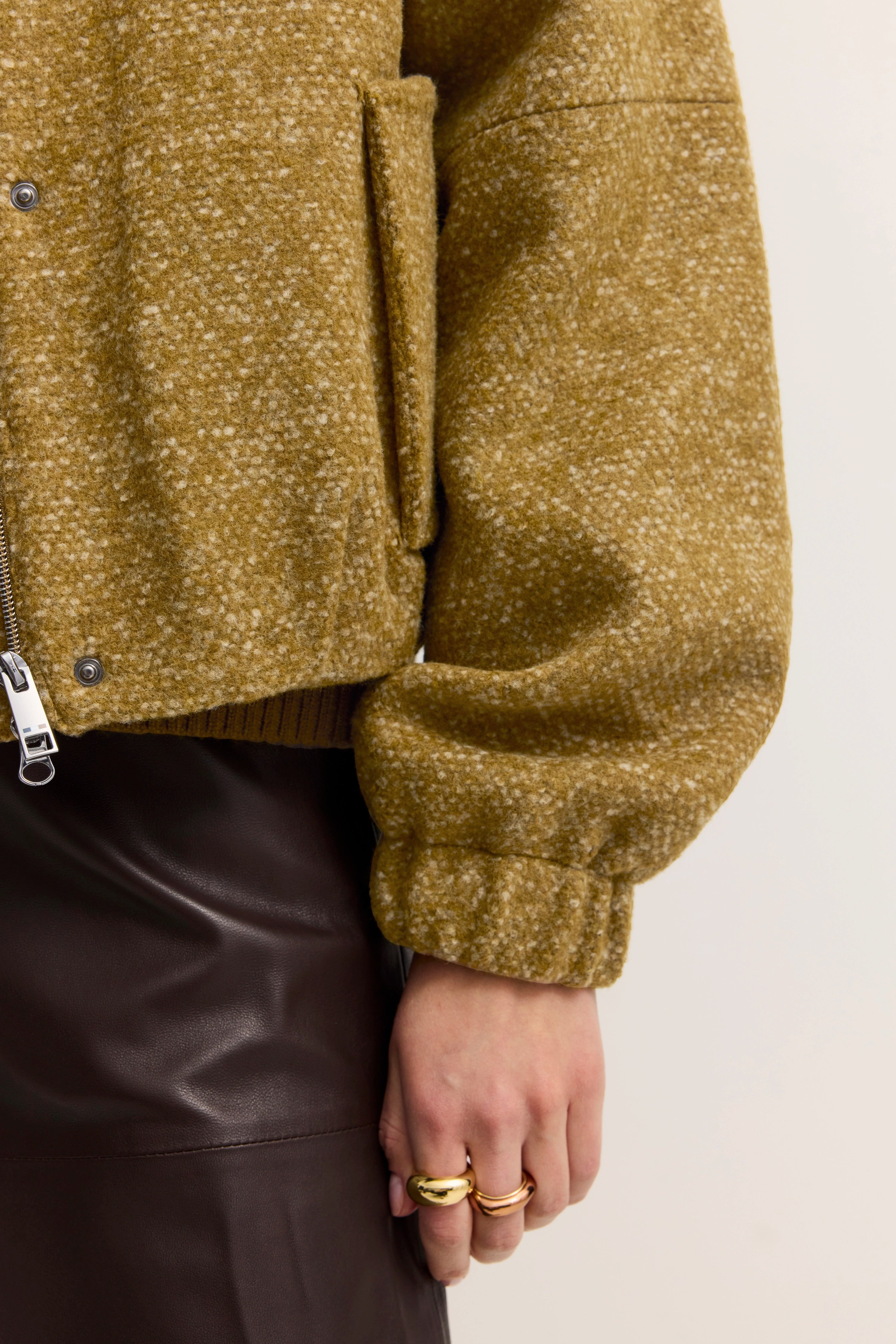 Gelbe Wolljacke mit braunem Lederrock, Detailaufnahme.